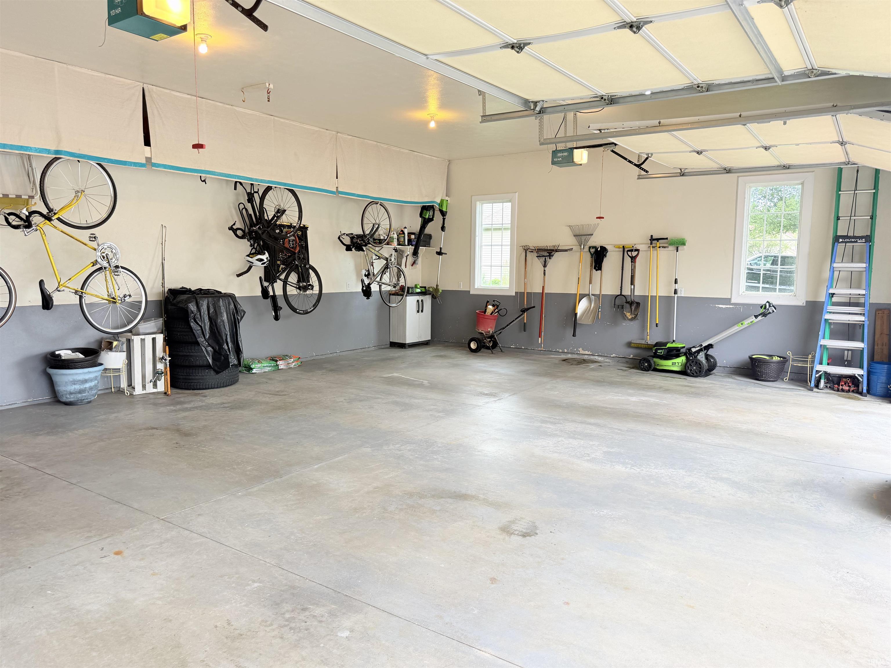 Spacious garage featuring a concrete floor, two large windows, and an overhead garage door