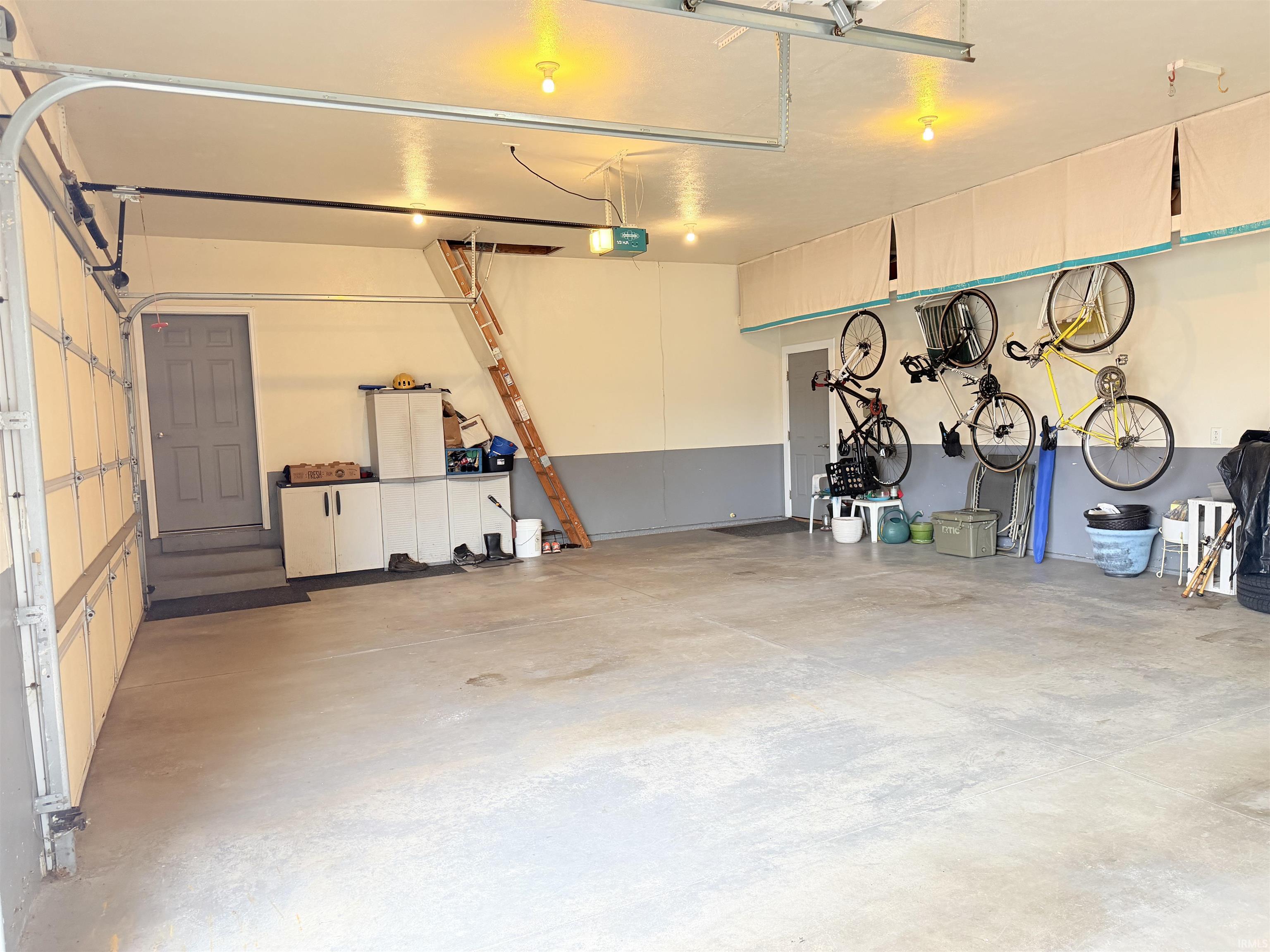 Spacious garage with concrete flooring, overhead lighting, and an automatic garage door opener