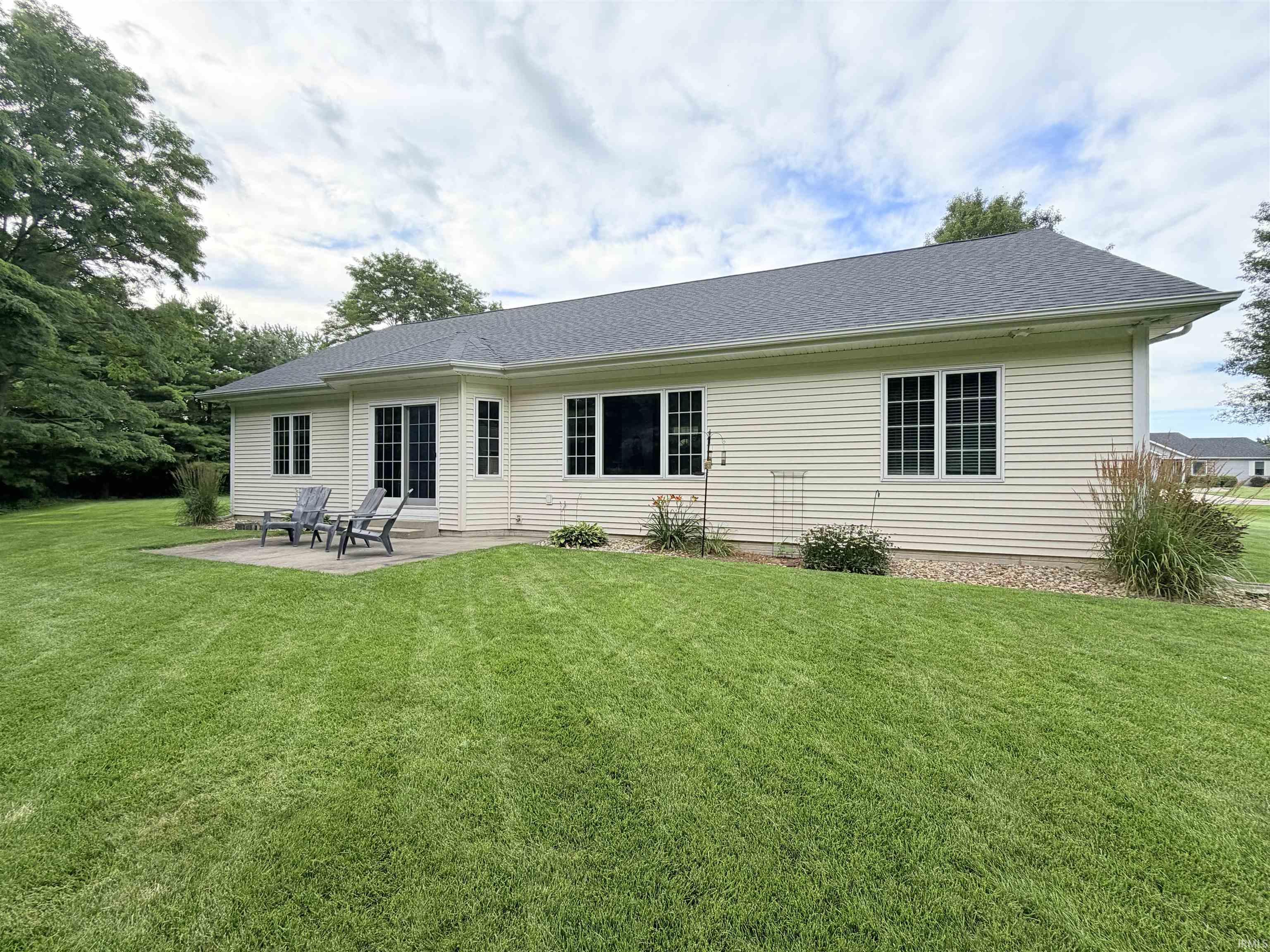 Rear exterior with light-toned horizontal siding, a dark shingle roof, and multiple windows