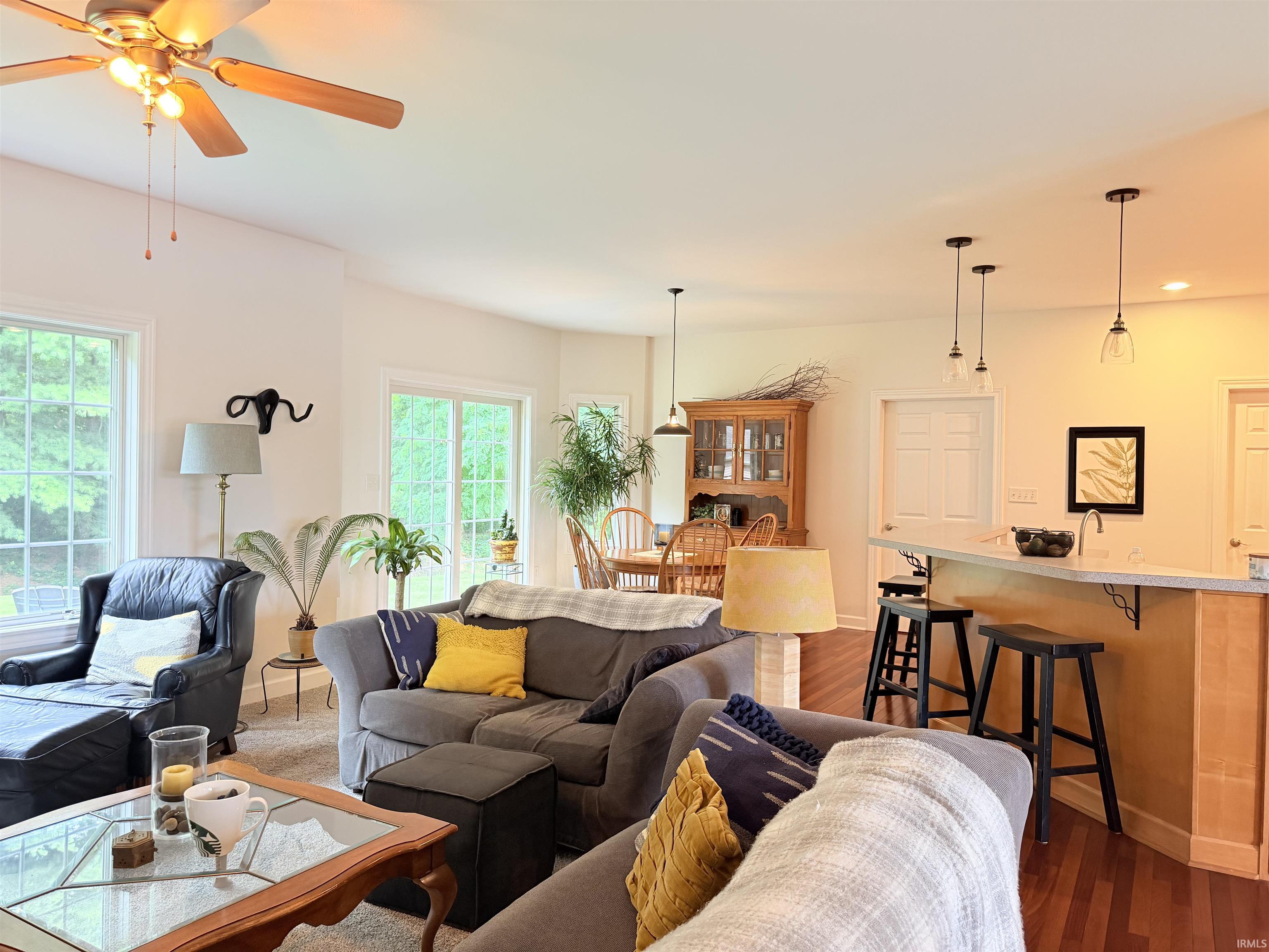 Open-concept living space featuring wood-finish flooring, a breakfast bar with pendant lighting, and multiple windows