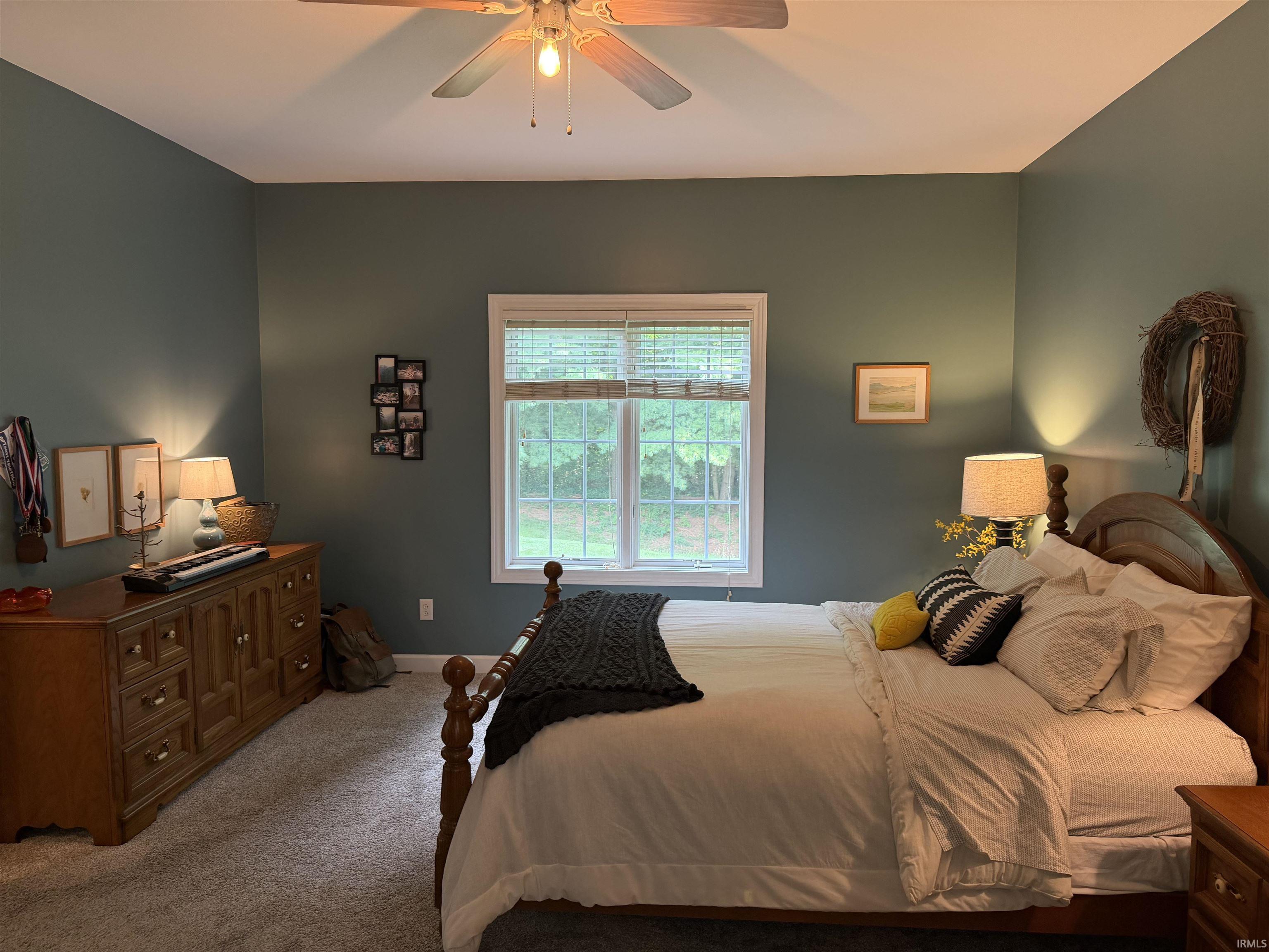 Carpeted room with a vaulted ceiling, a centered window with blinds, and a ceiling fan with integrated lighting