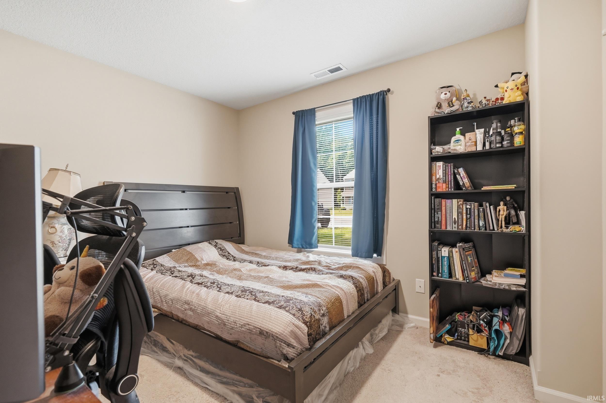 Bedroom featuring neutral wall paint, a window with blue curtains, and a ceiling light fixture