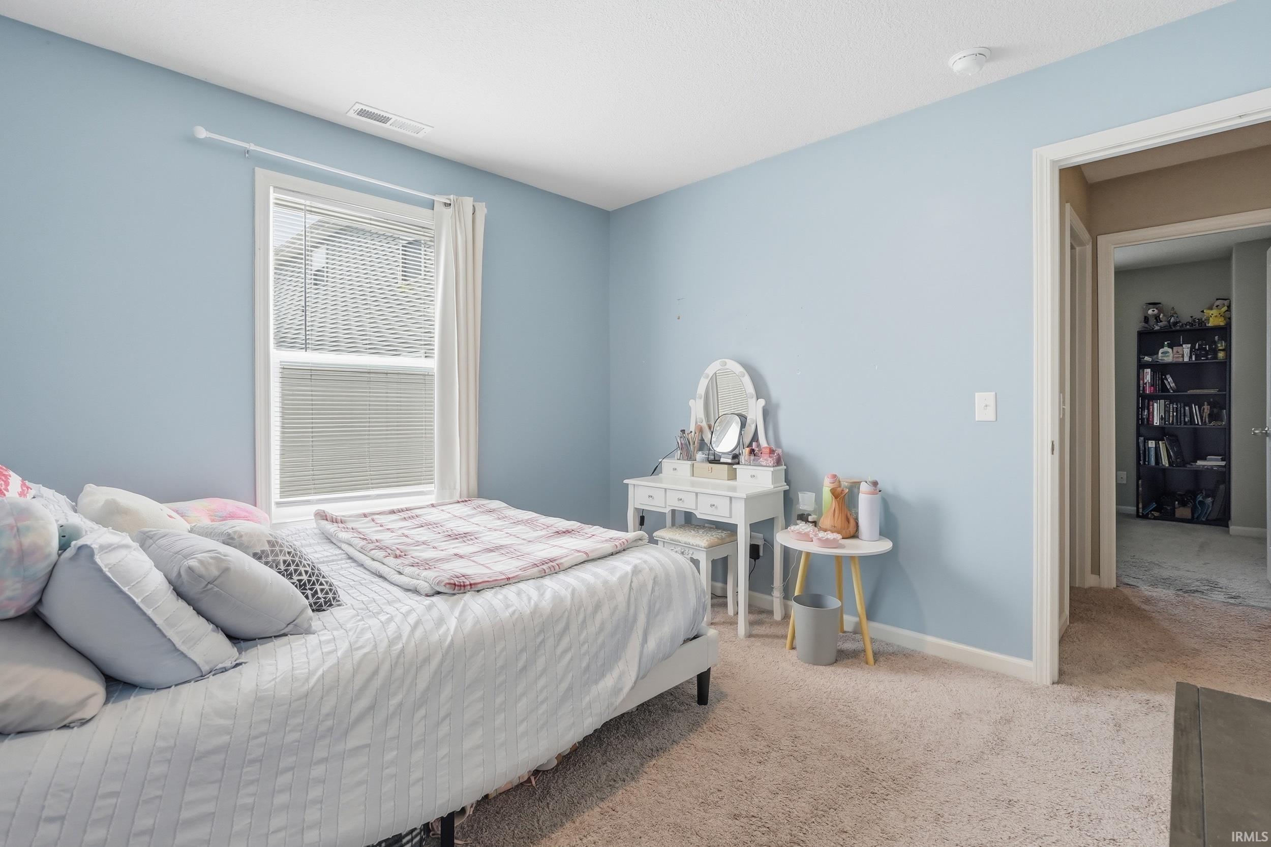 Carpeted room featuring a single window with blinds and an open doorway