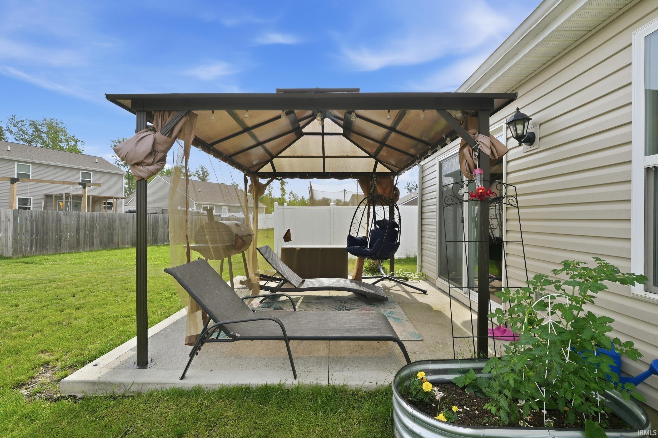Concrete patio featuring a gazebo with a fabric canopy and mesh screening