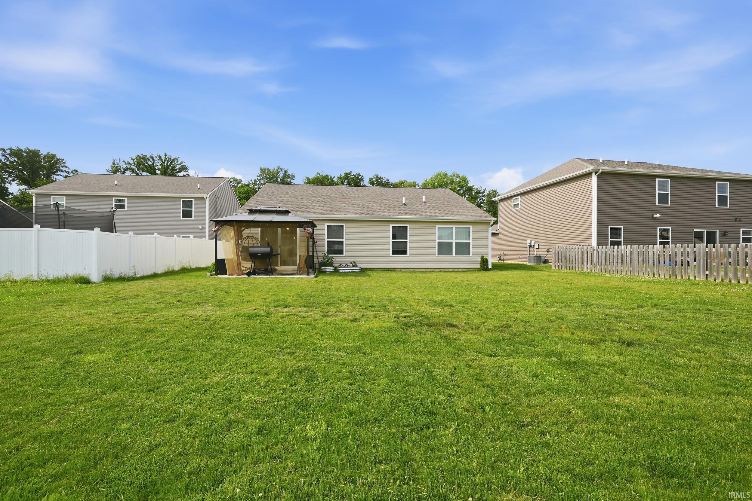 Expansive rear yard featuring a large grassy area, a privacy fence, and a gazebo