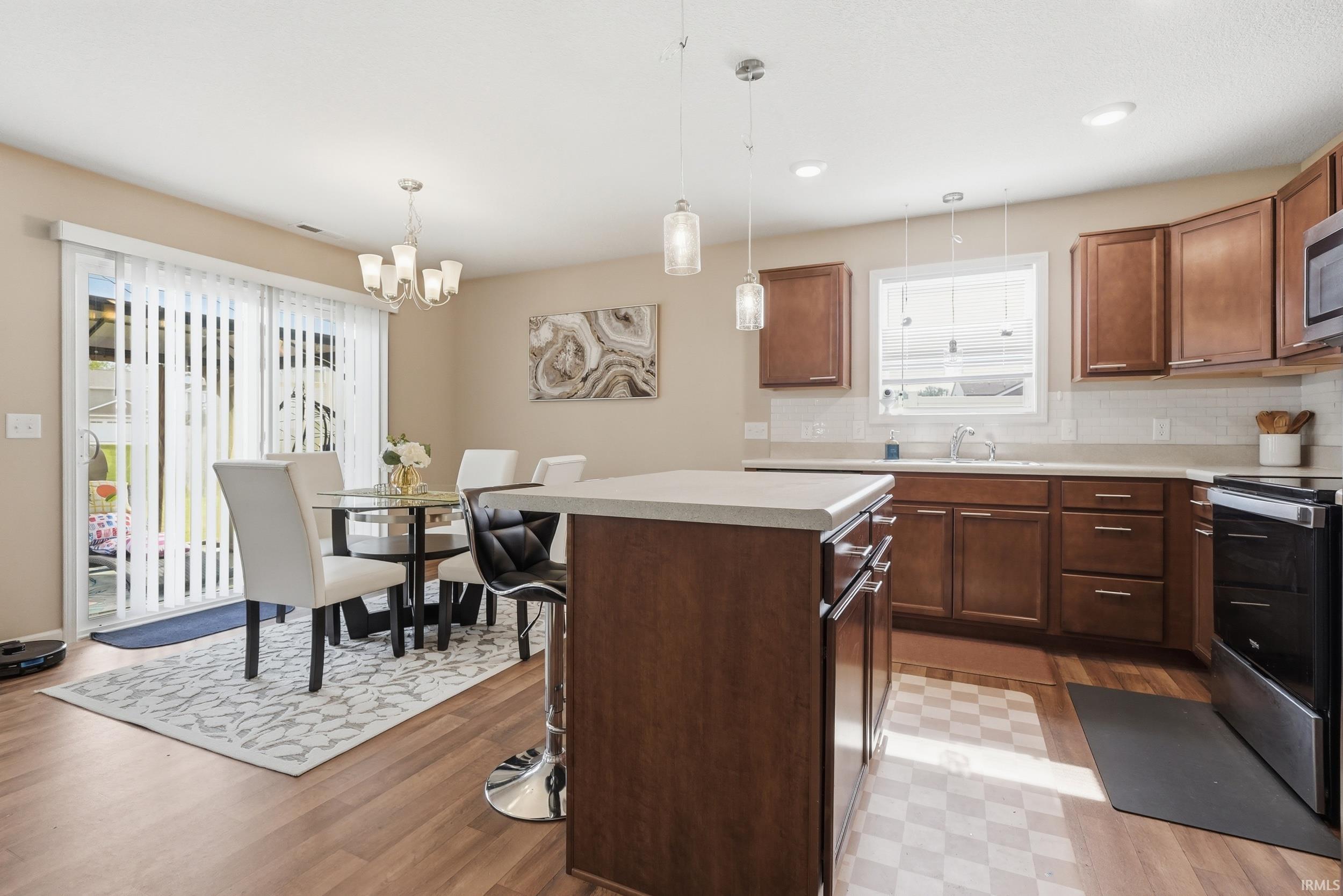 Open-concept kitchen and dining area featuring wood-finish flooring, warm wood cabinetry, and light countertops