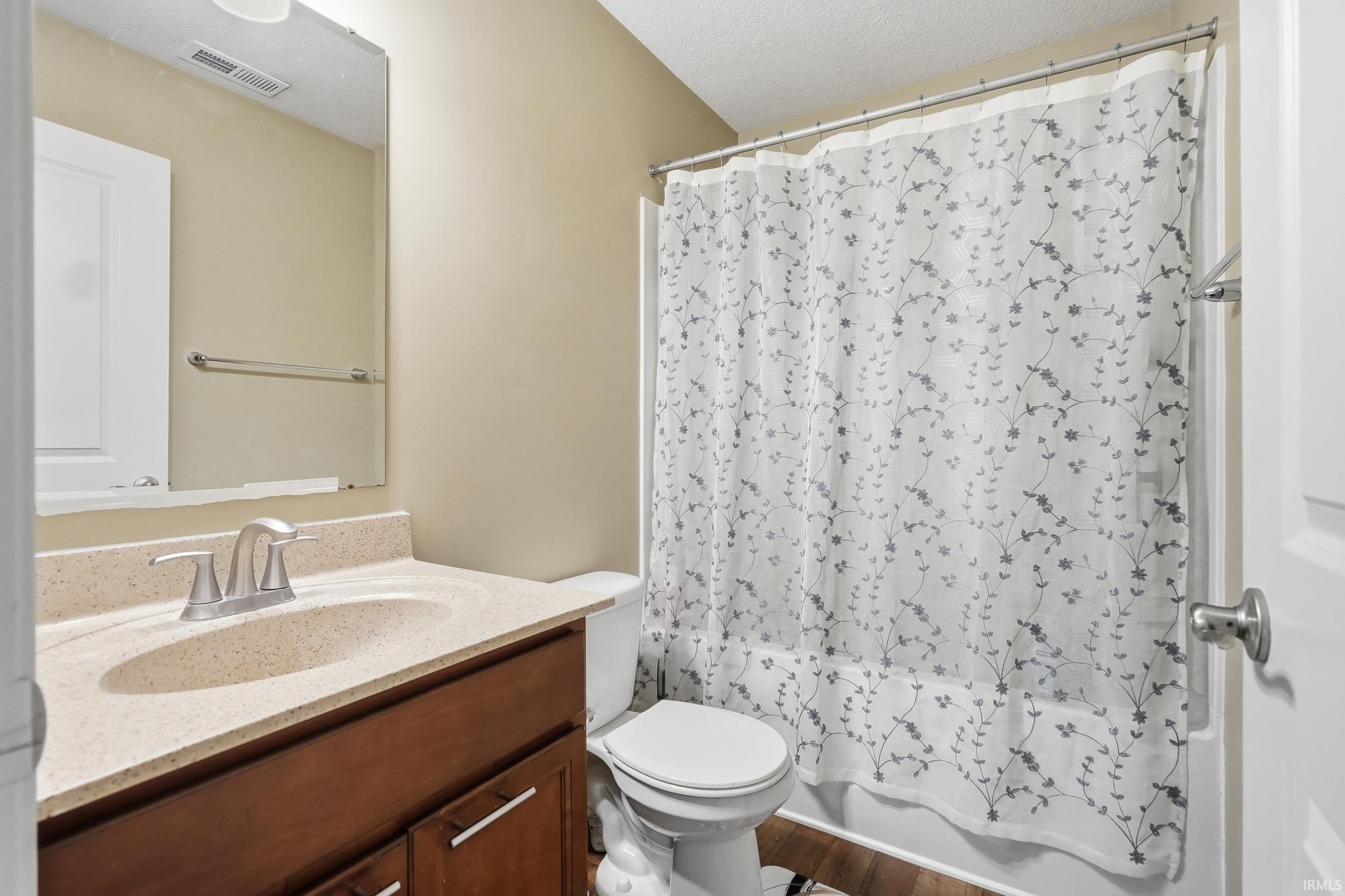 Bathroom featuring a wood-finish vanity with a light-toned countertop, an integrated sink, and a brushed nickel faucet