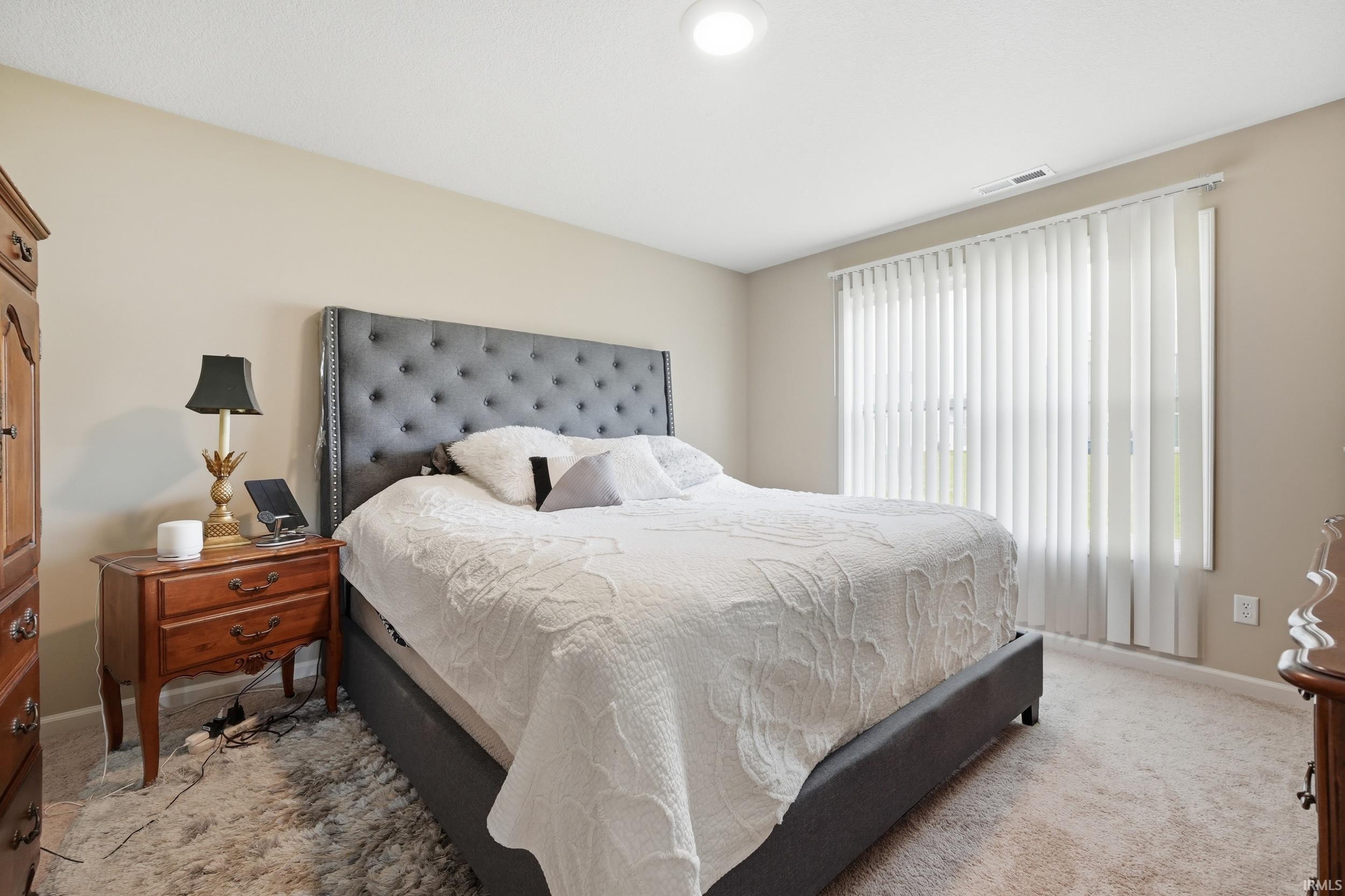 Recessed lighting illuminates this room, featuring light-colored walls and soft carpet flooring
