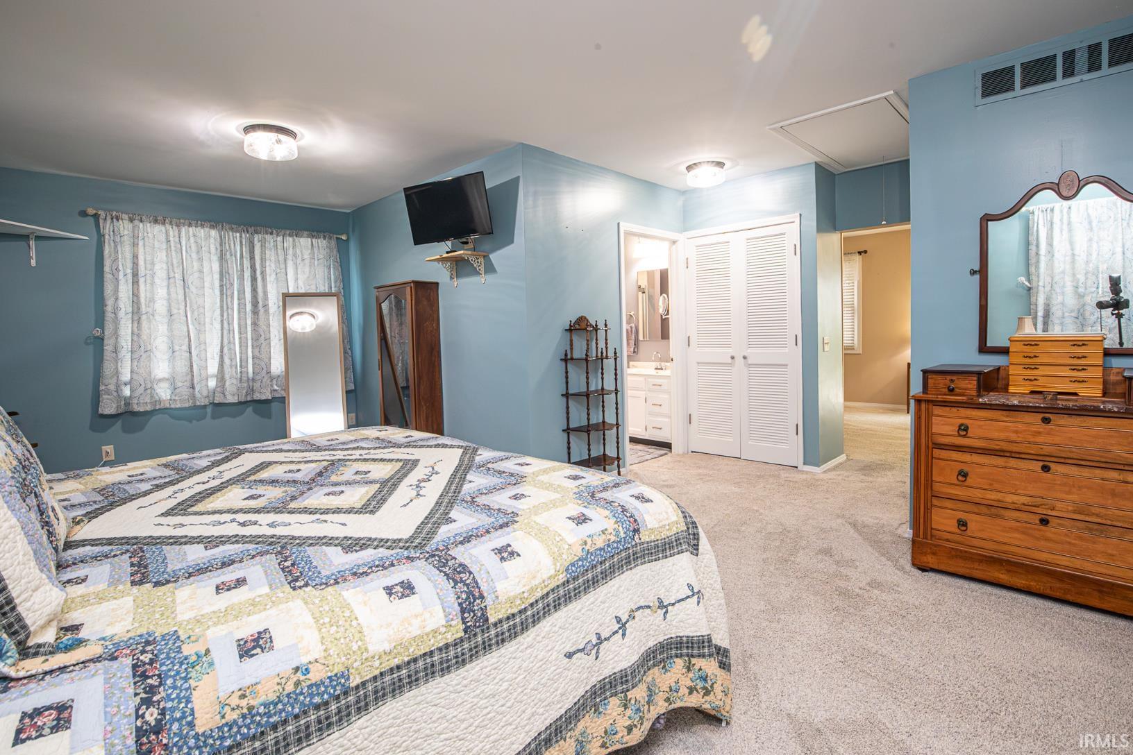 Spacious room featuring light blue walls, soft grey carpeting, and white louvered bifold doors