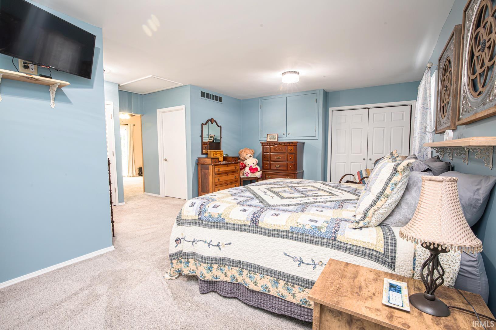 Carpeted room featuring light blue walls, built-in cabinetry, and double white bifold closet doors