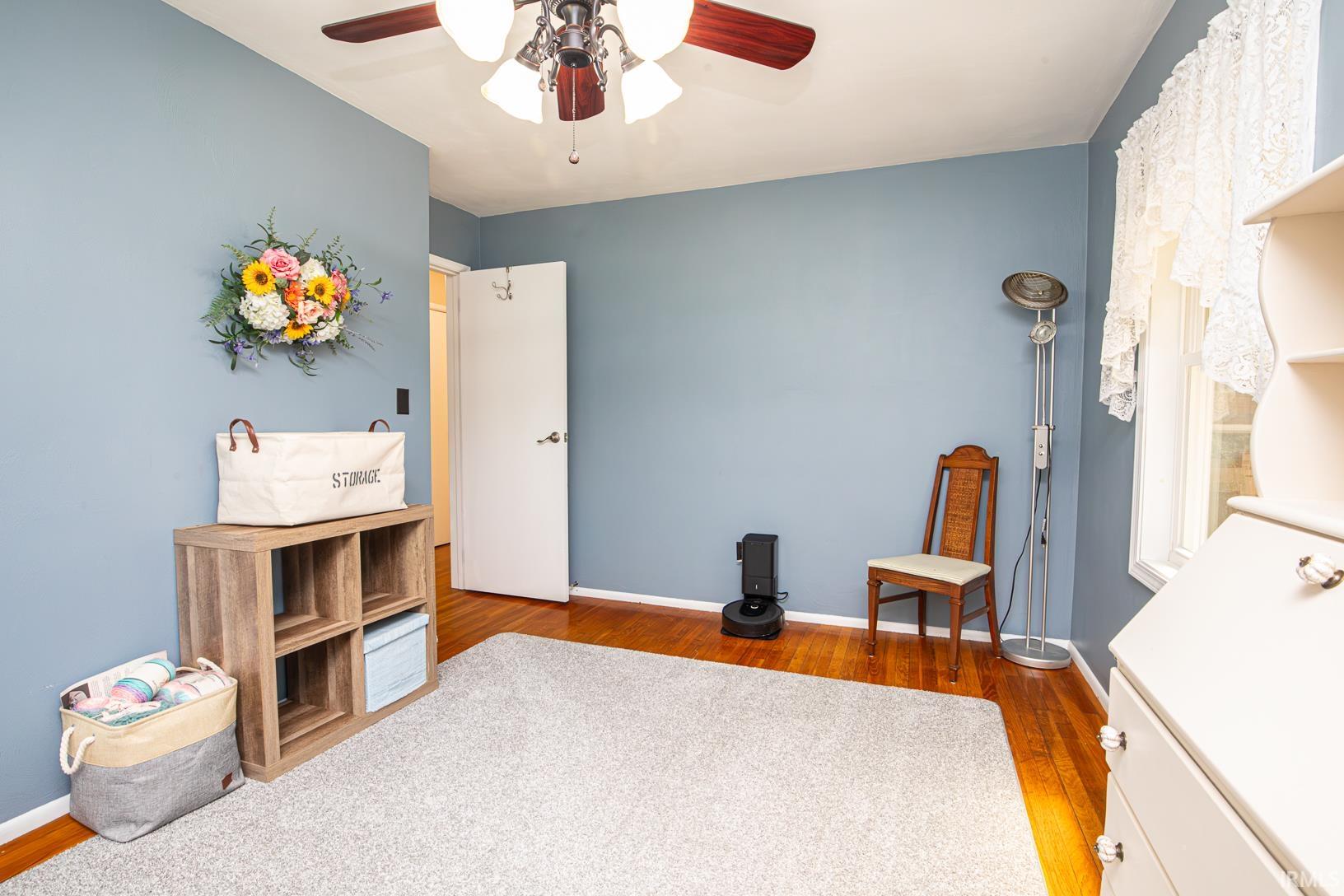 Room with wood-finish flooring and a central ceiling fan