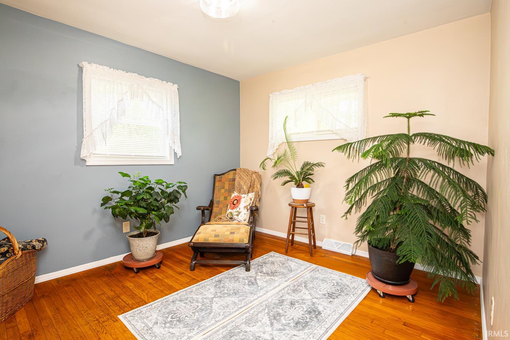 Room featuring rich wood-finish flooring, white baseboards, and a combination of blue and beige painted walls