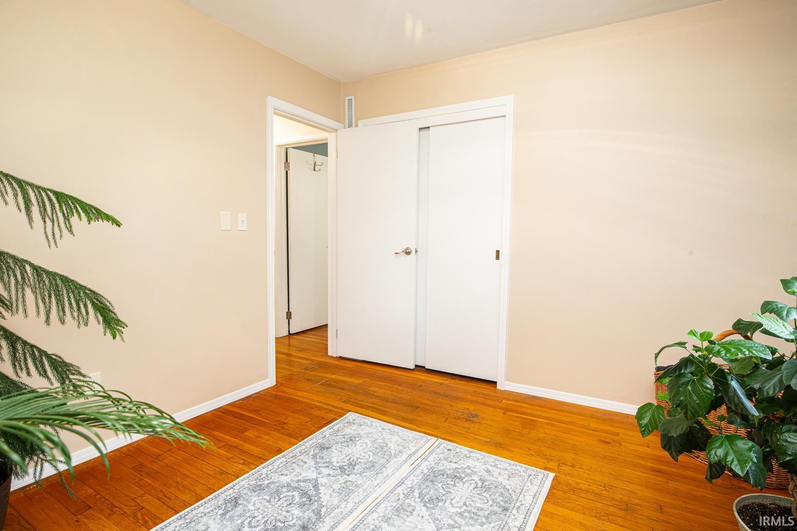 Hardwood flooring throughout, with a door leading into another space and a closet featuring white sliding doors