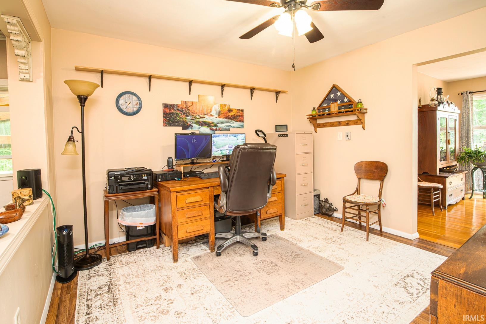 Dedicated office space featuring wood-finish flooring, a ceiling fan with integrated lighting, and a neutral wall color