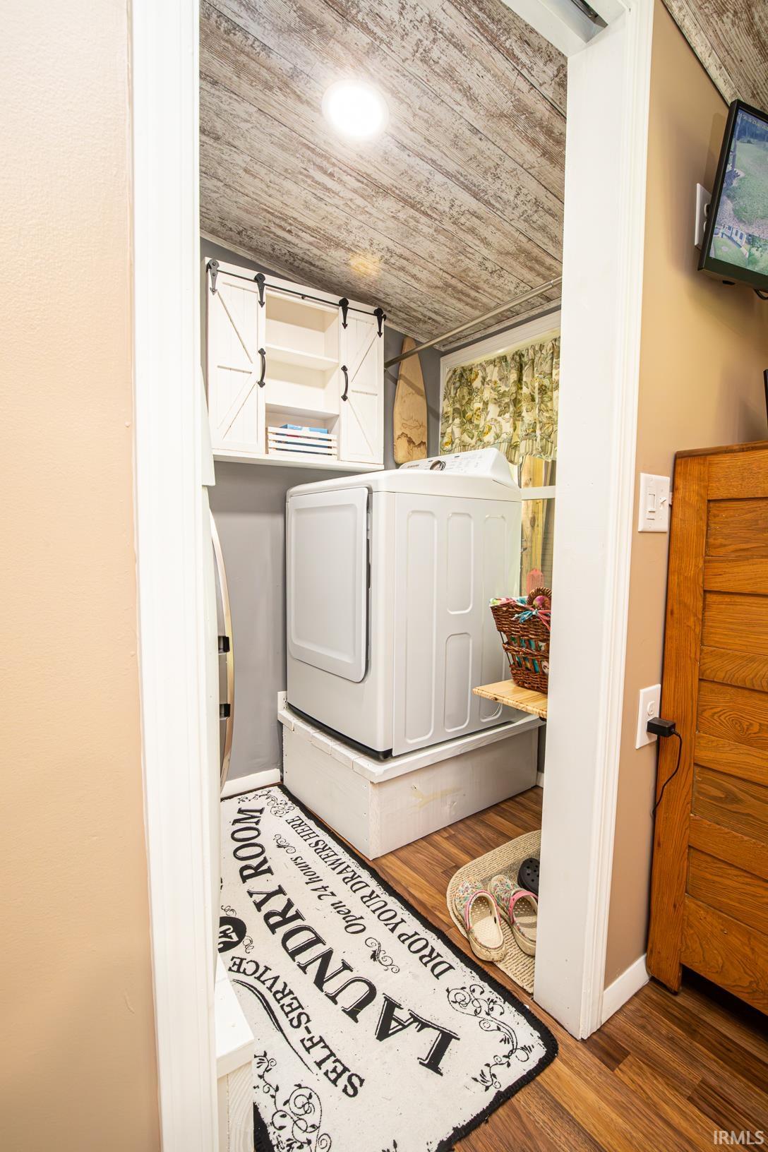 Dedicated laundry area featuring a wood-finish ceiling, built-in washer and dryer, and wood-finish flooring