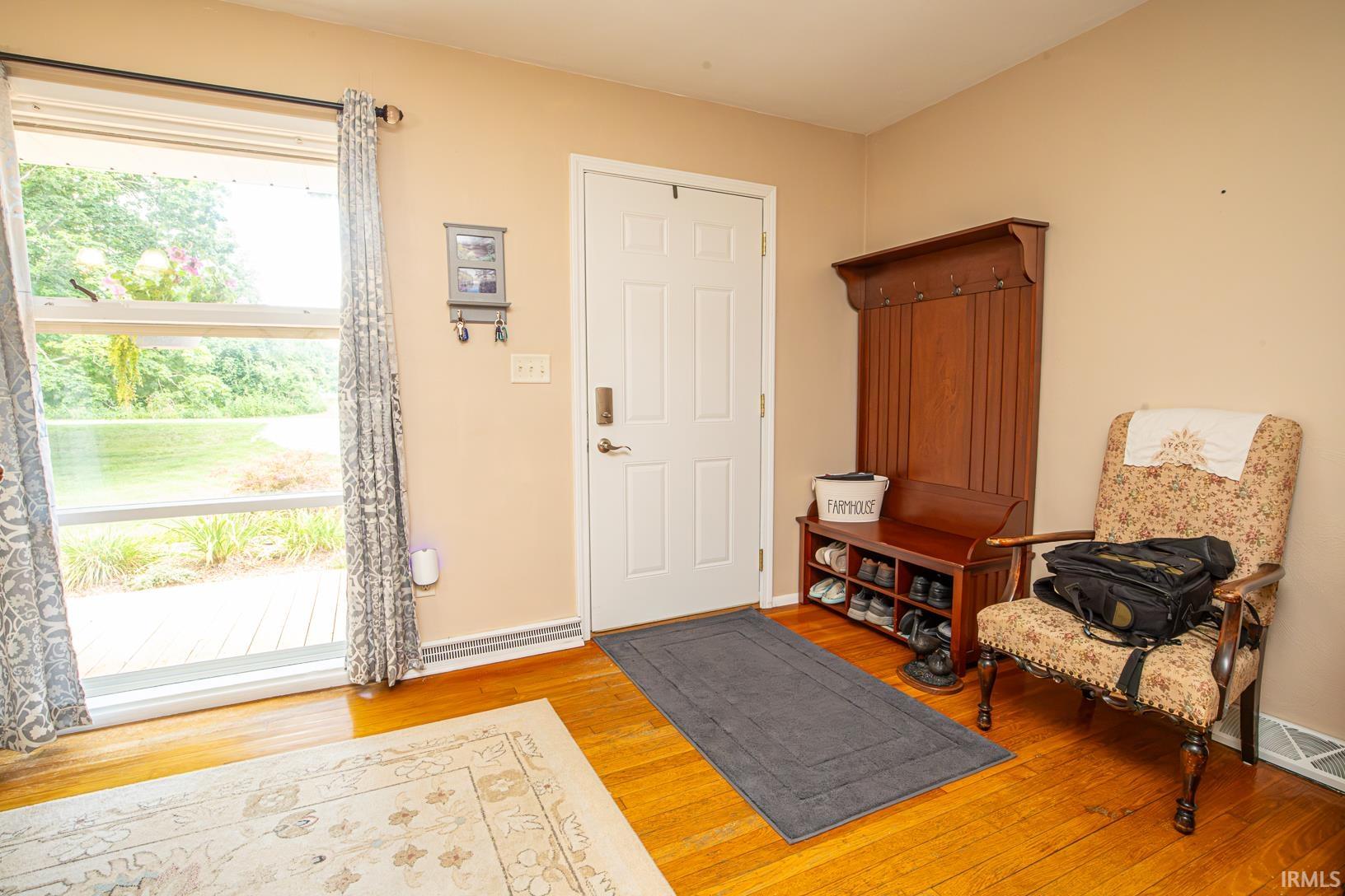 Entryway featuring a white paneled door, wood-finish flooring, and a large window overlooking a natural landscape