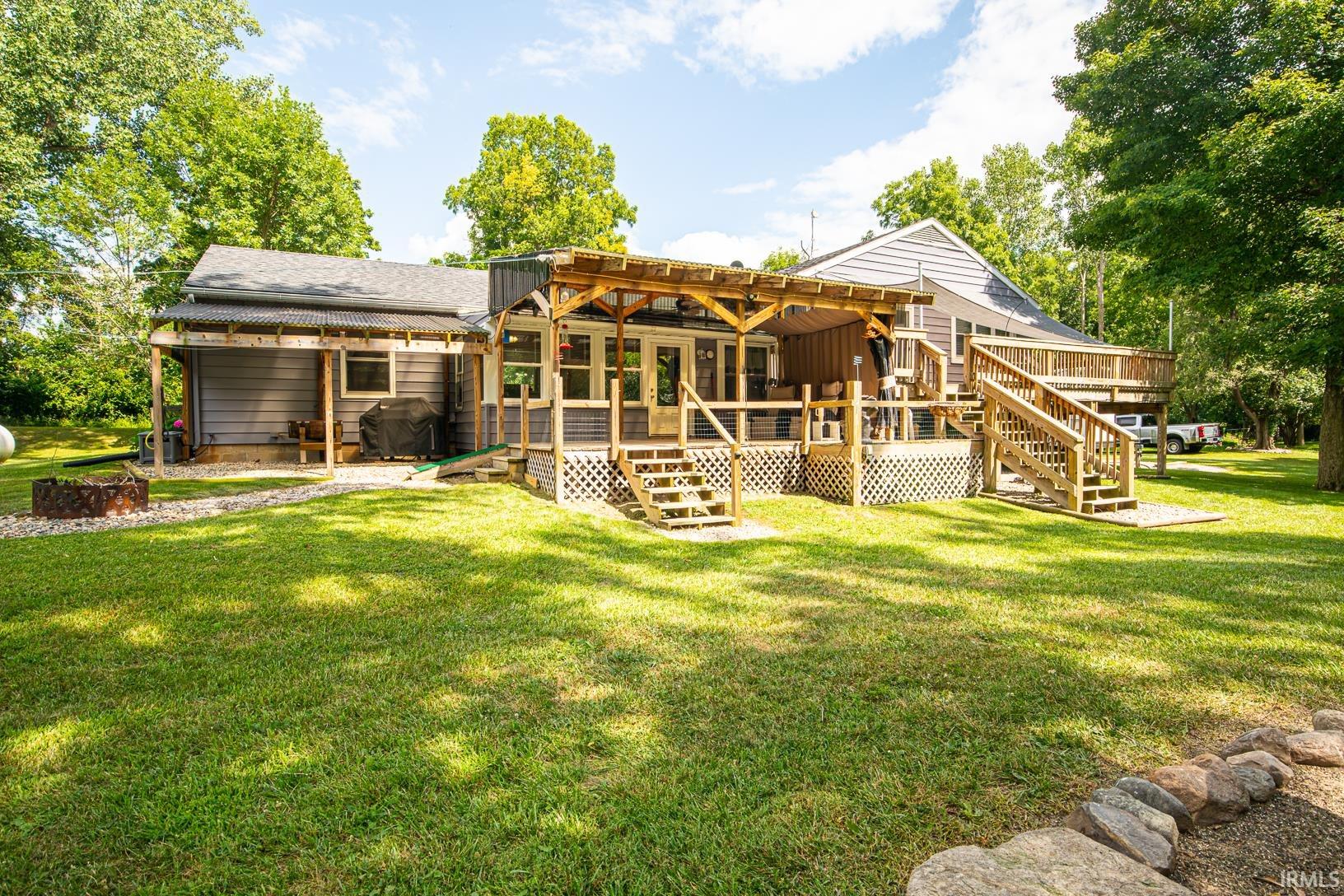 Spacious backyard with a multi-level wooden deck featuring stairs, railings, and lattice skirting