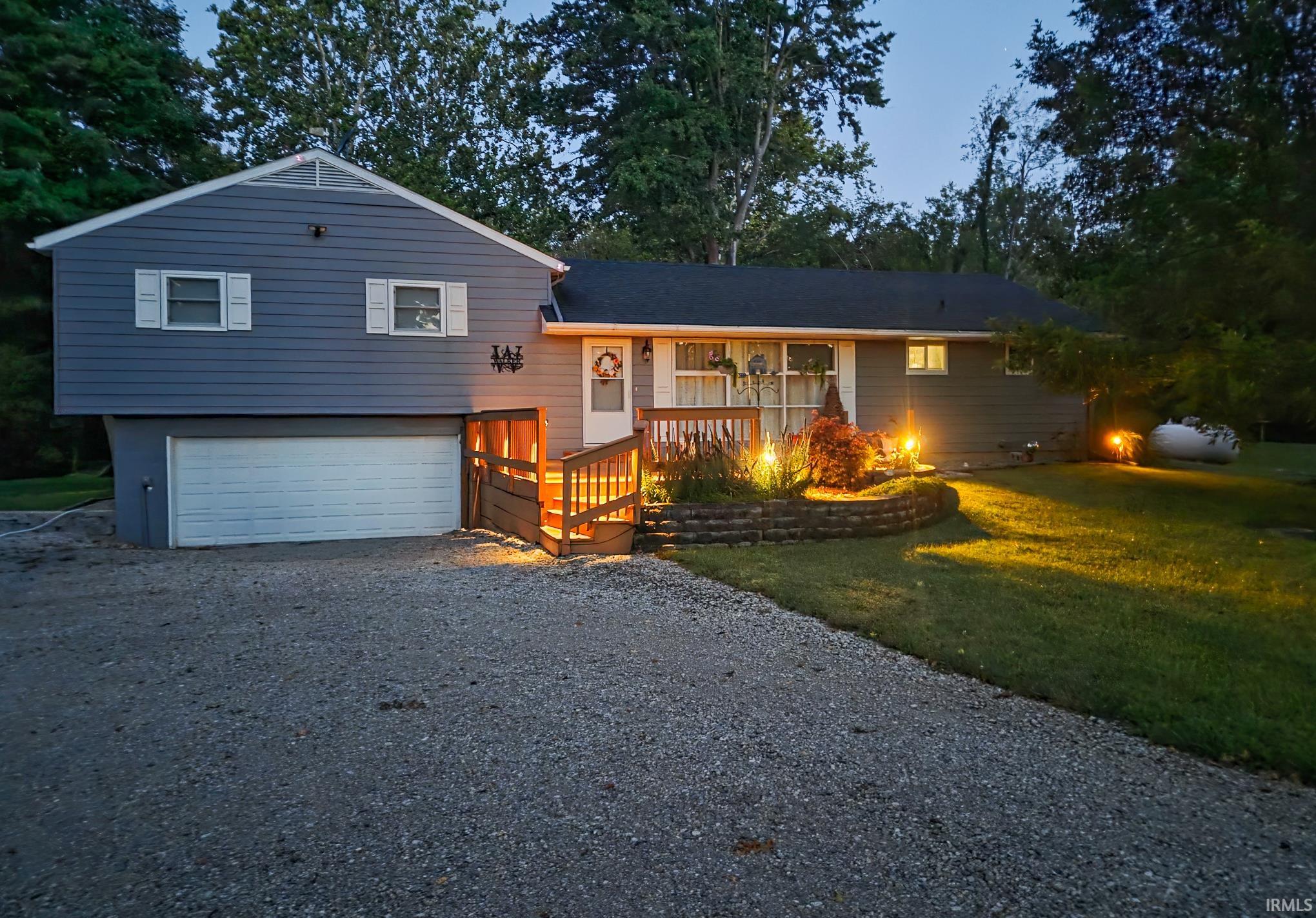 Split-level home featuring blue siding, white window shutters, and a dark shingle roof