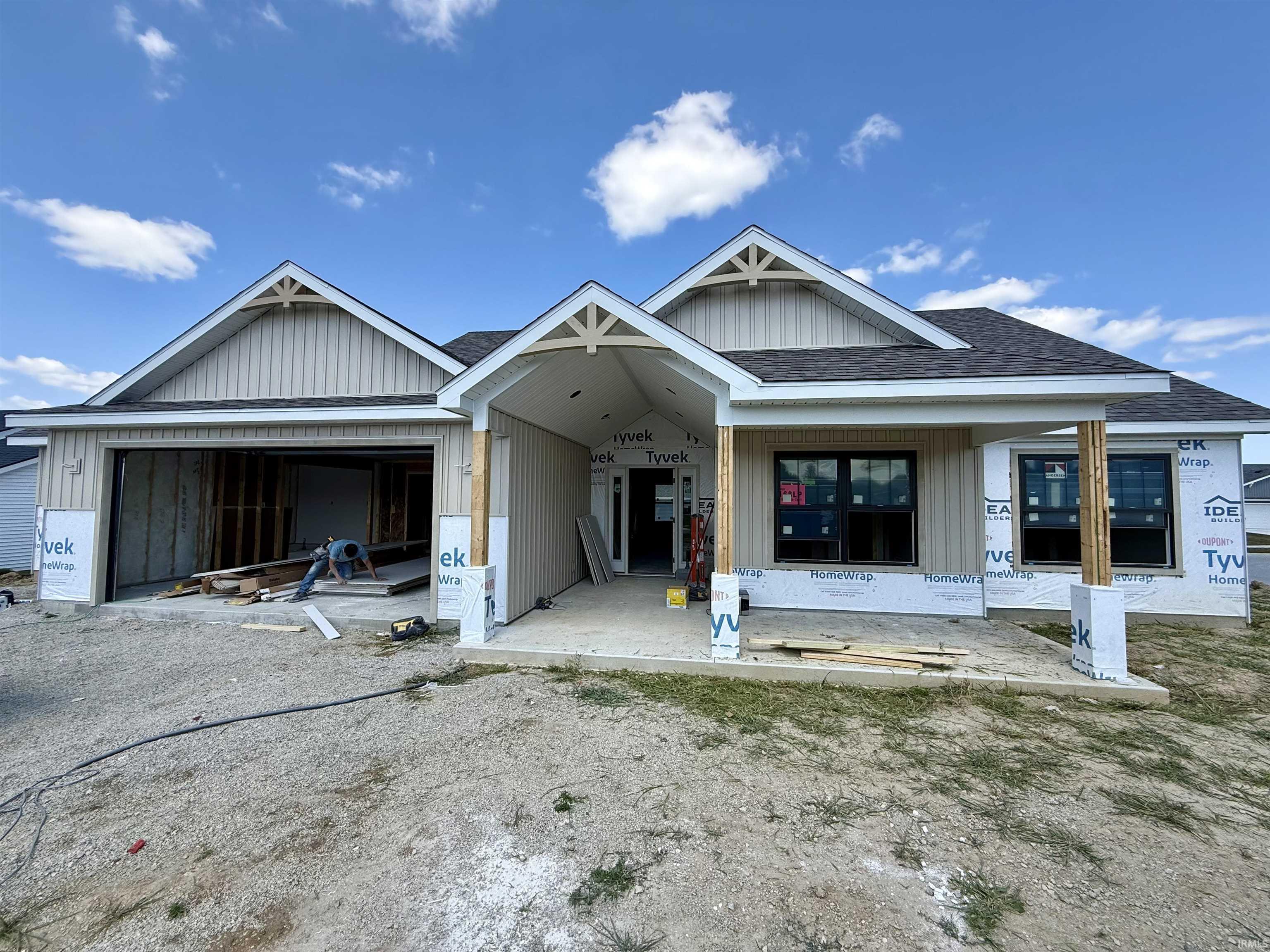 Contemporary new construction featuring light-toned vertical siding, a dark shingle roof, and prominent gabled architectural details