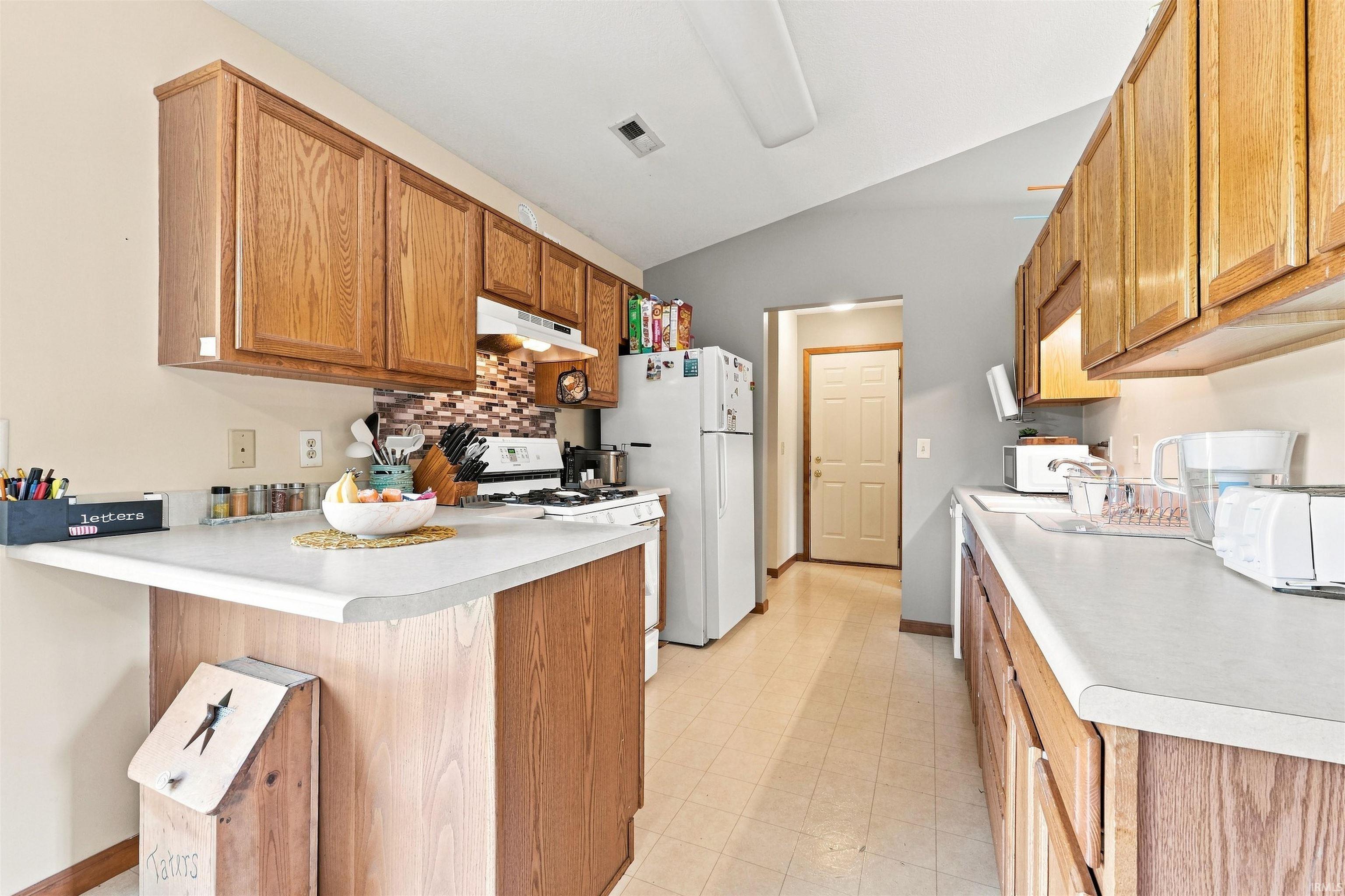 Kitchen featuring light wood-finish cabinetry, light-toned countertops, and a tile backsplash