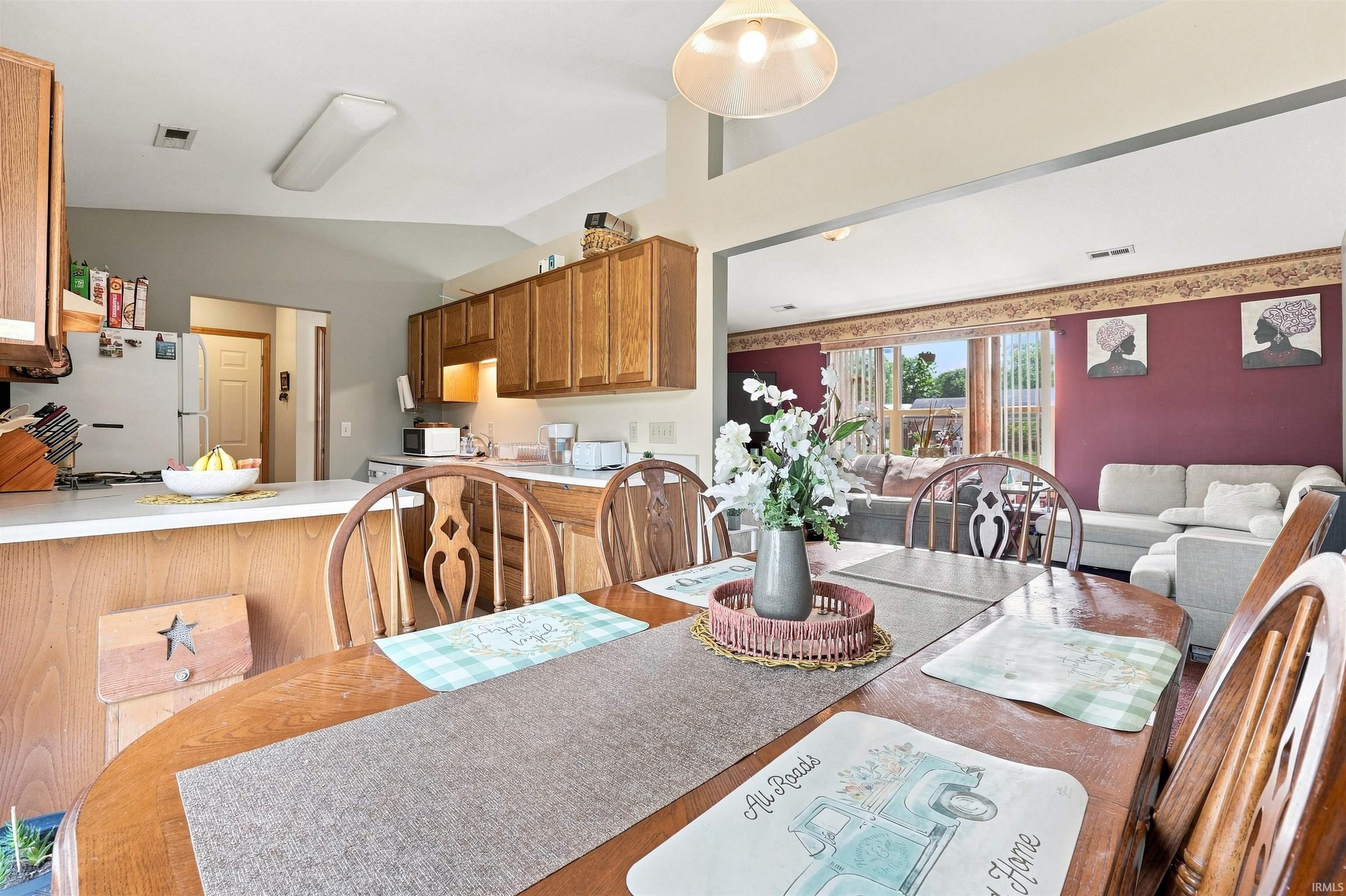 Open-concept dining area featuring a vaulted ceiling and direct sightline to the kitchen