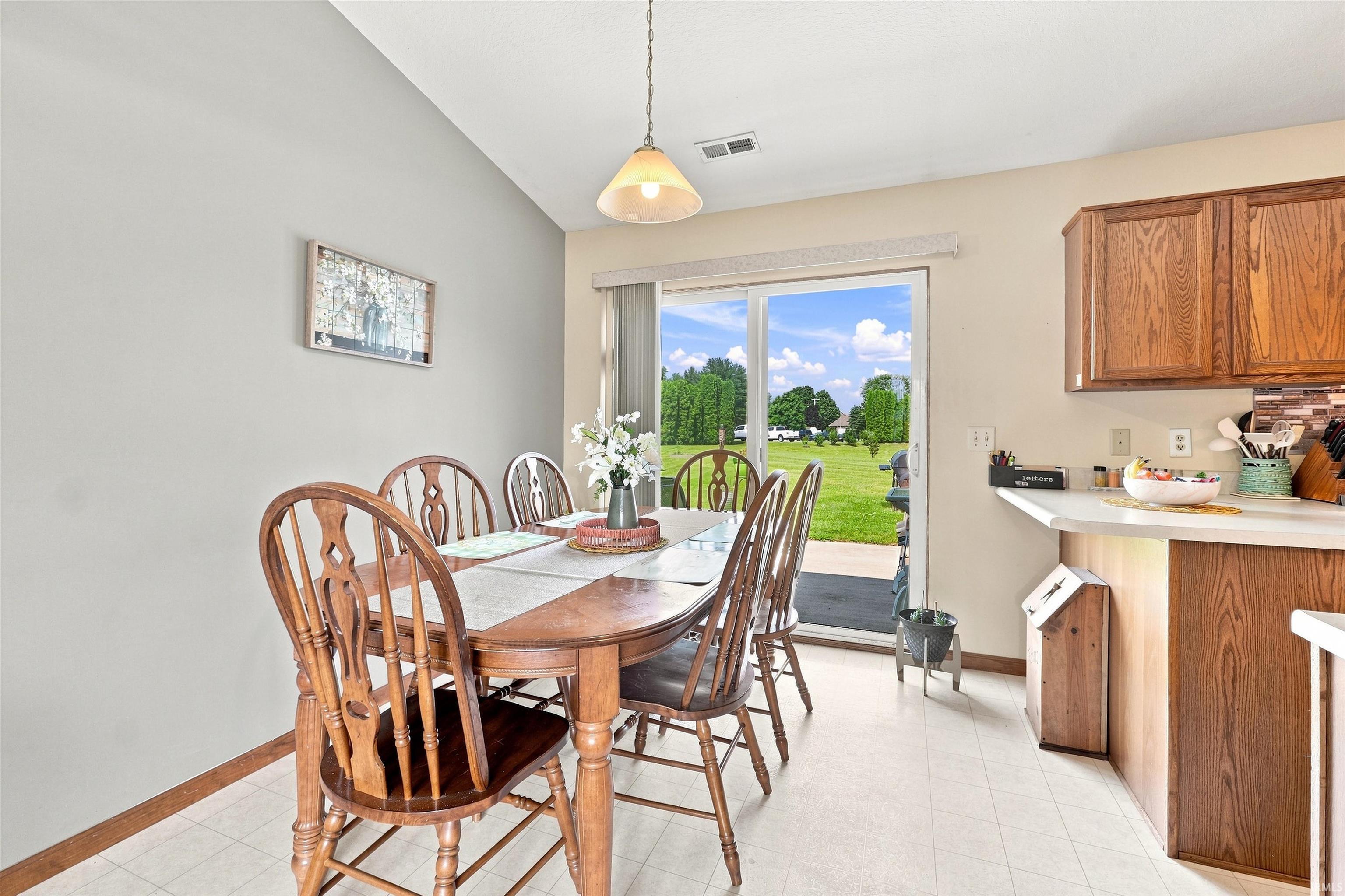 Dining area with vaulted ceiling and direct patio access via sliding glass doors