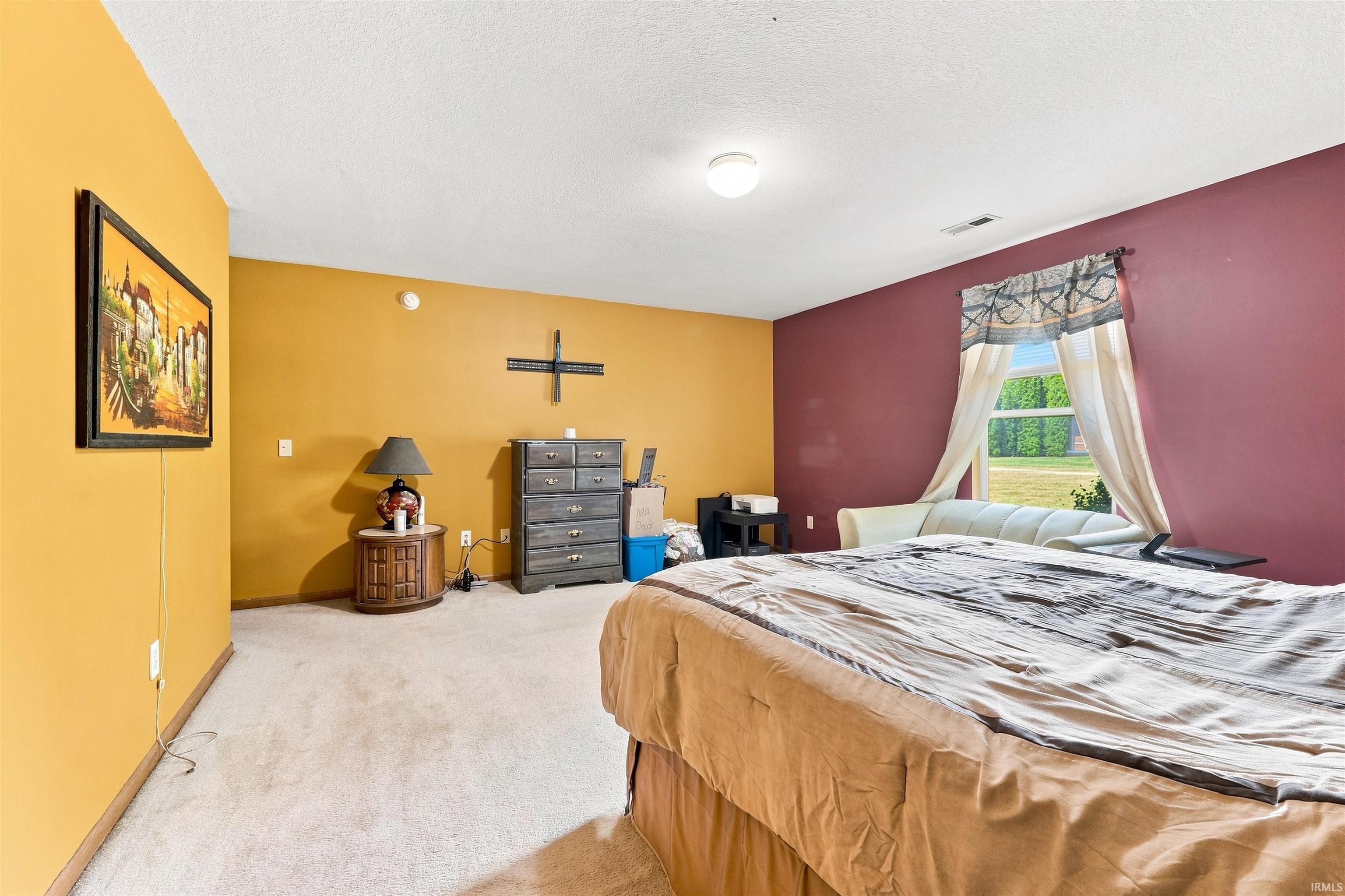 Carpeted room with a ceiling light fixture and a window with a curtain rod
