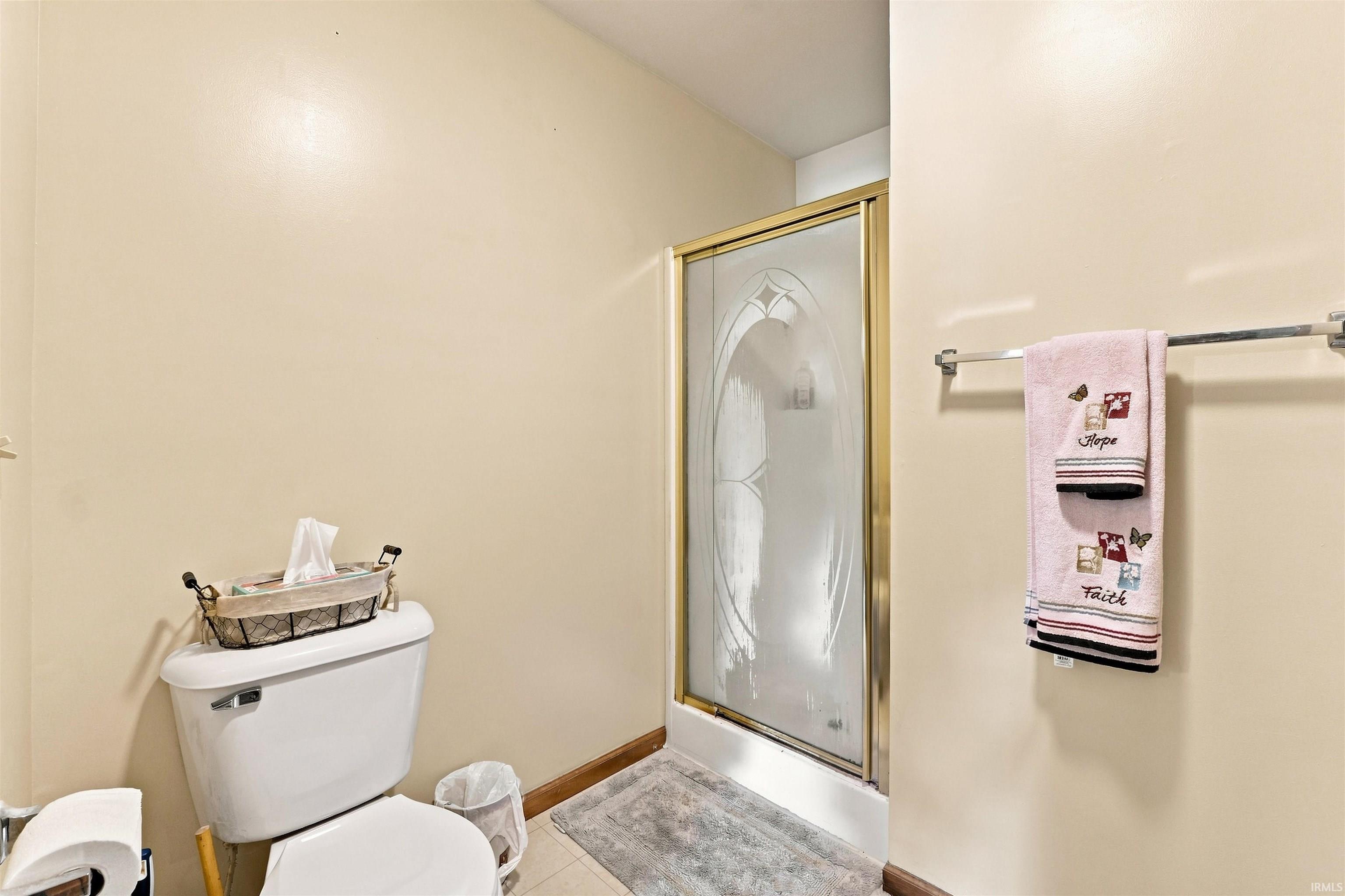 White toilet with a gold-framed shower enclosure featuring frosted glass with an etched design