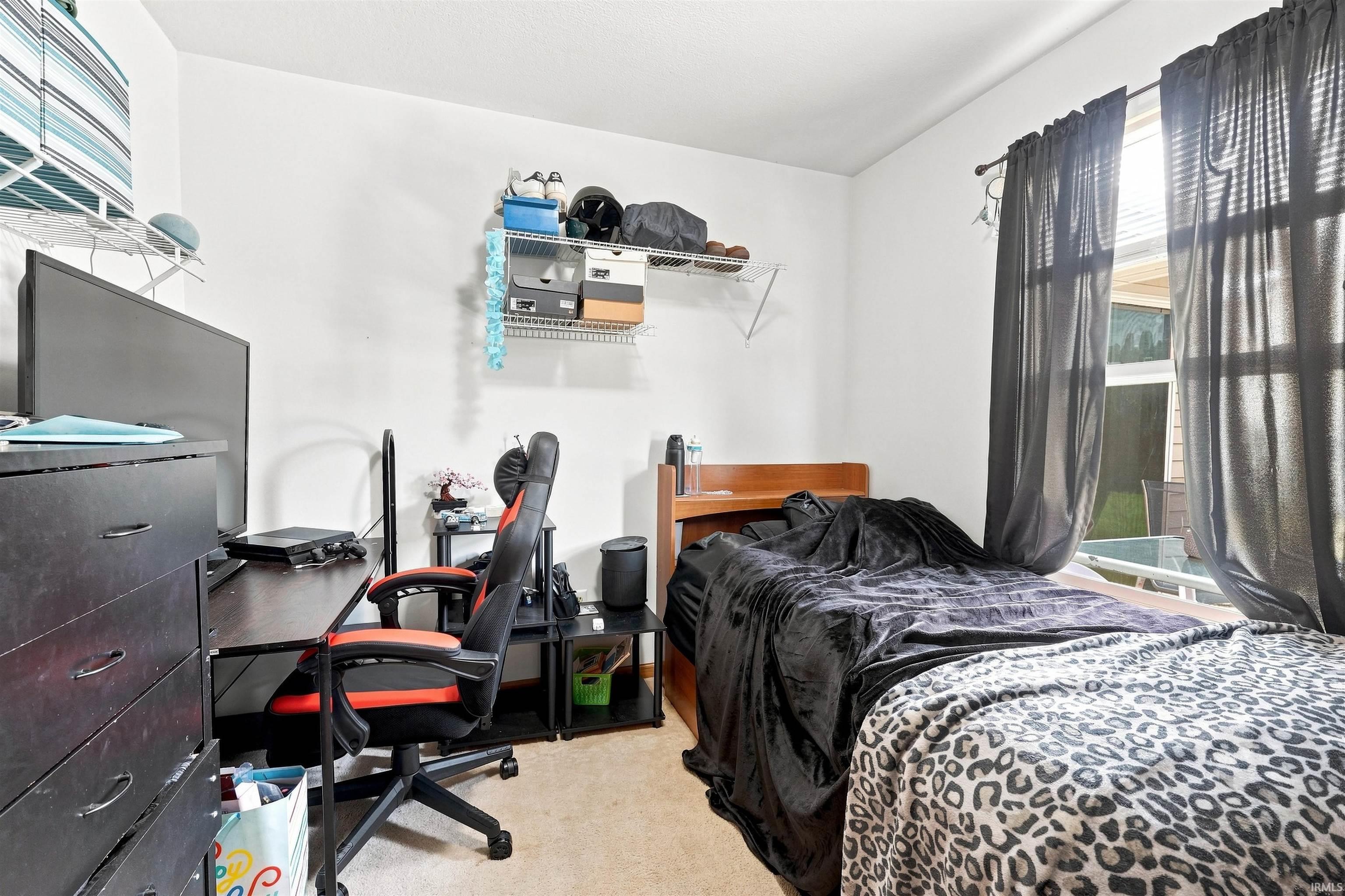 Bedroom featuring carpeted flooring, a window with horizontal blinds, and a built-in wire shelving system