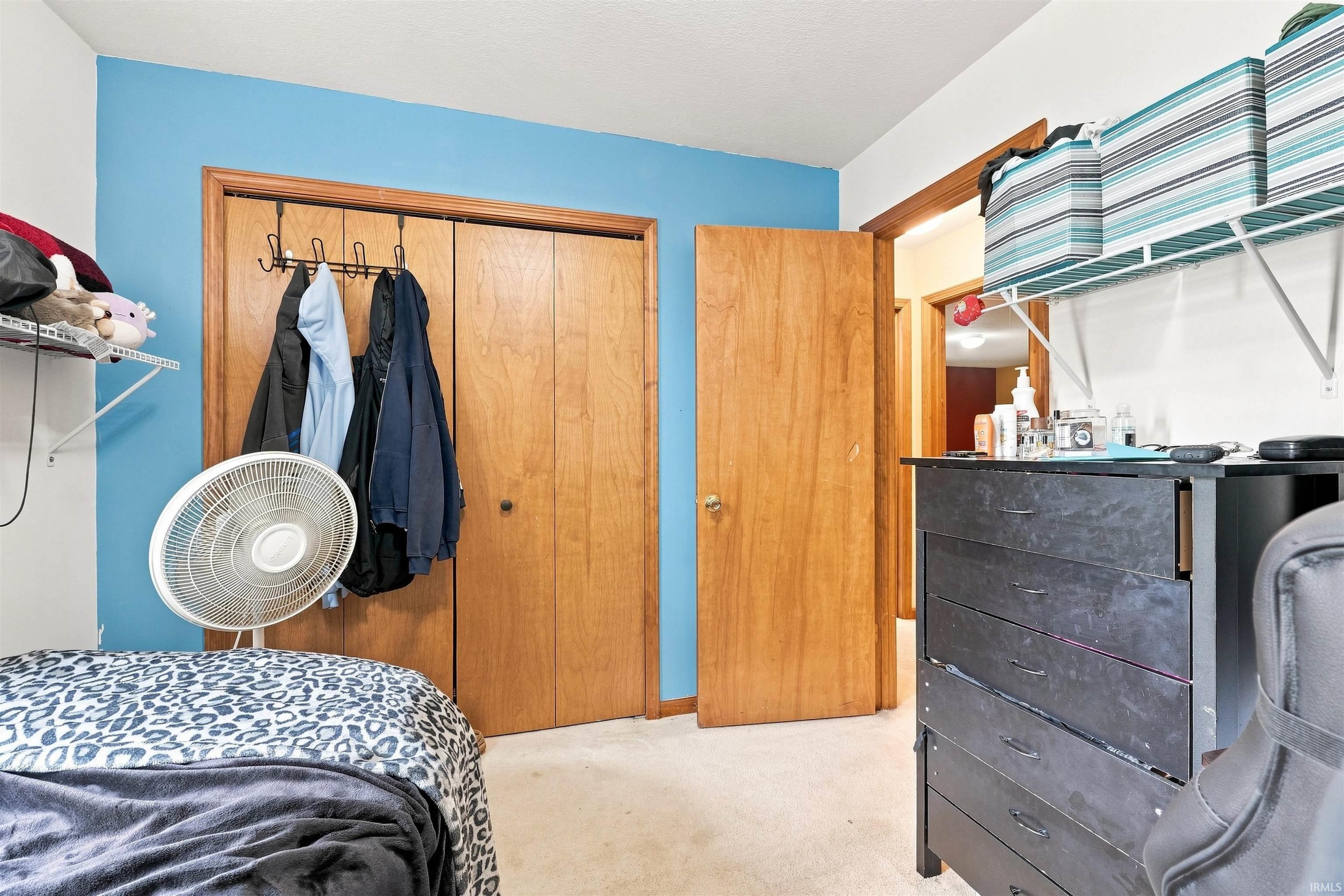 Carpeted room featuring a built-in closet with bi-fold wood doors and a separate wood-panel door