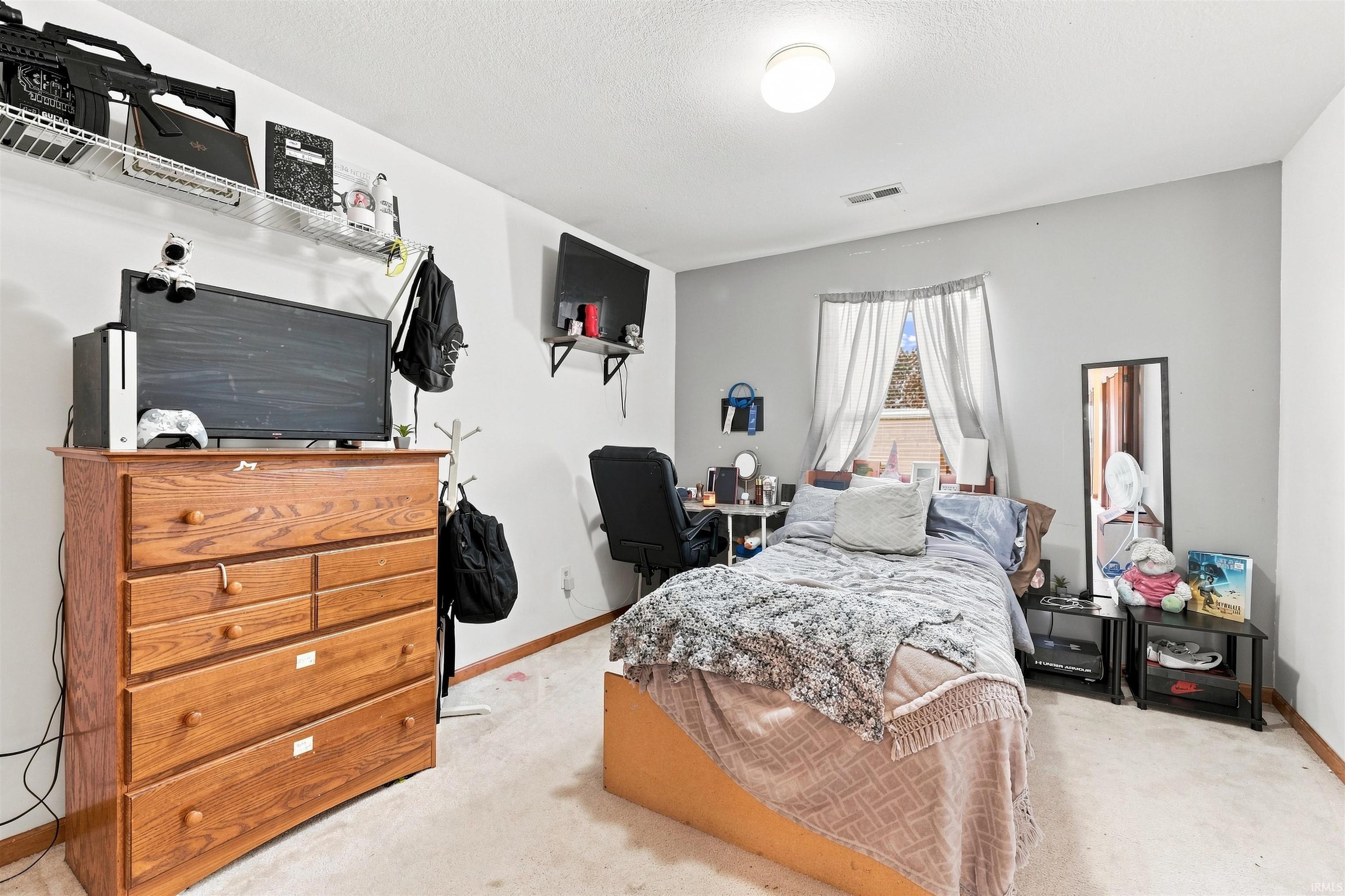 Bedroom featuring light gray walls, carpet flooring, and a single window with drapes