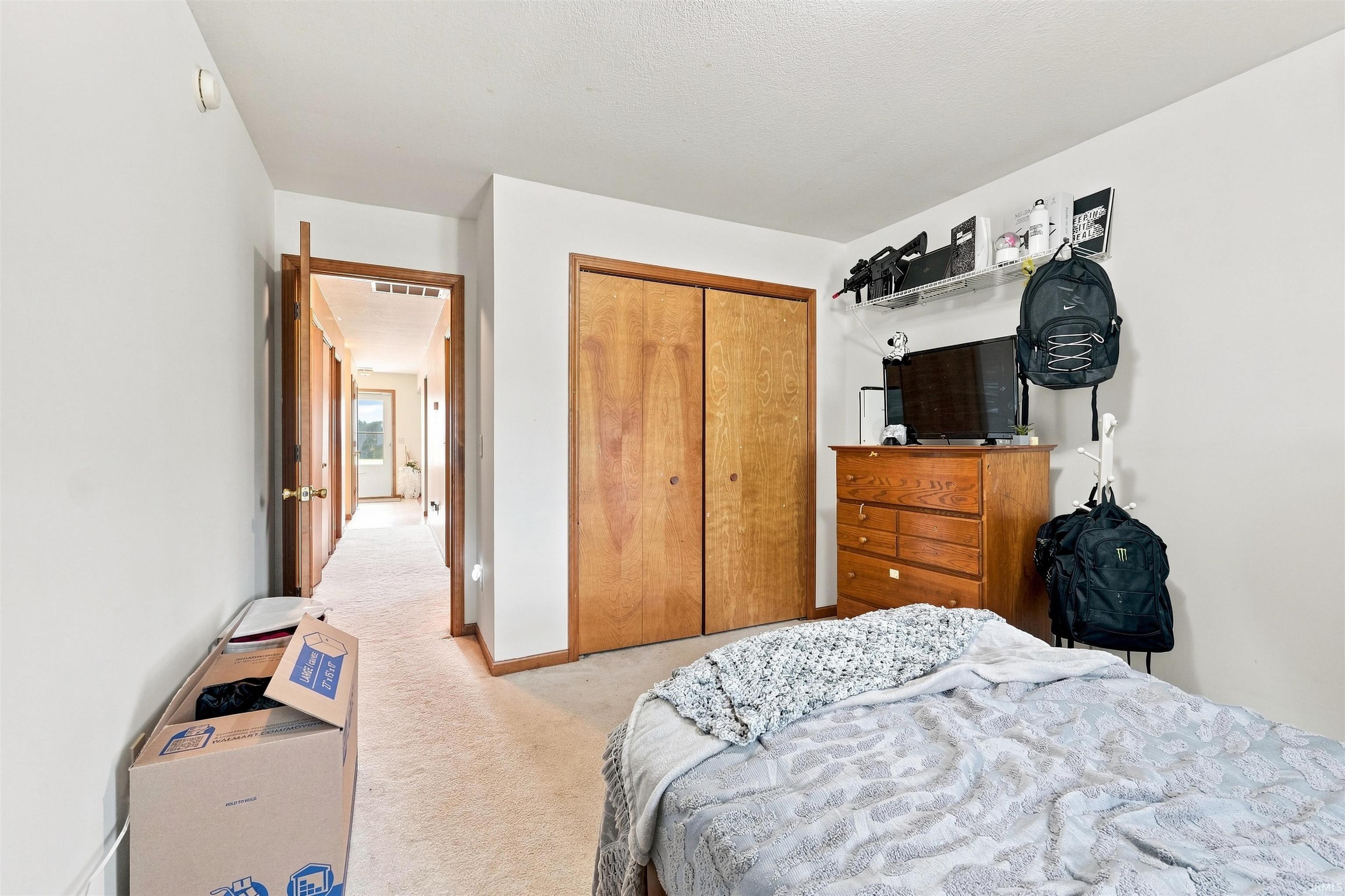 Bedroom with carpet flooring, wood-finish bi-fold closet doors, white walls, and a recessed ceiling light