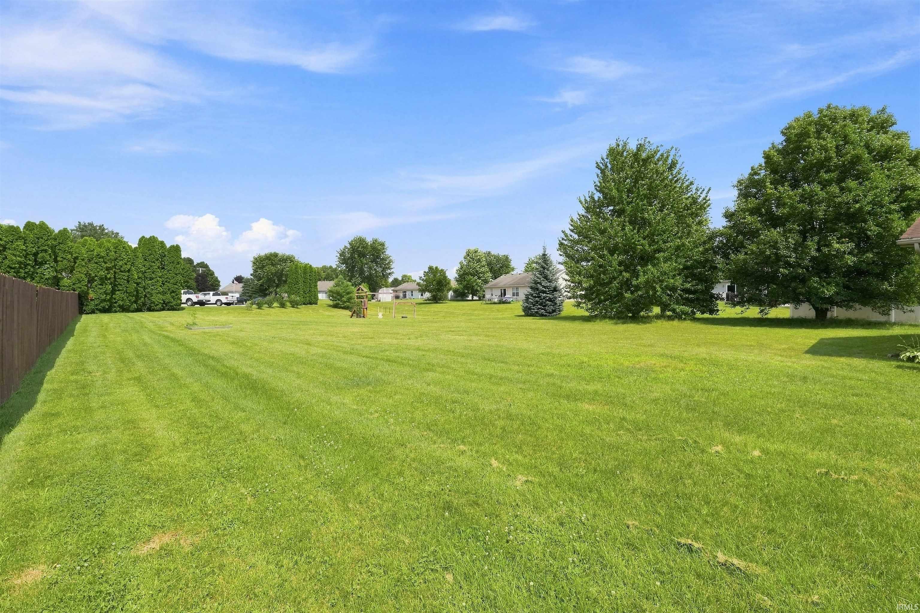 Expansive green lawn with a brown privacy fence along one border
