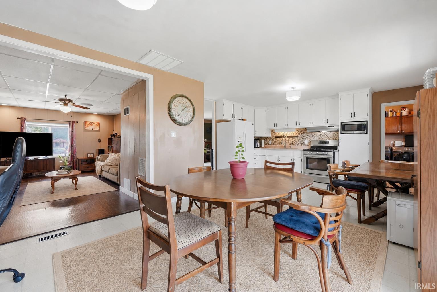 Open-concept kitchen and dining area featuring white cabinetry, stainless steel appliances, a tiled backsplash, and recessed lighting