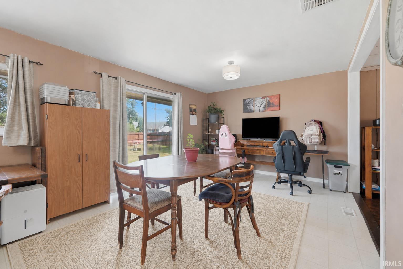 Spacious room featuring light-toned flooring, a sliding glass door to the exterior, and multiple windows