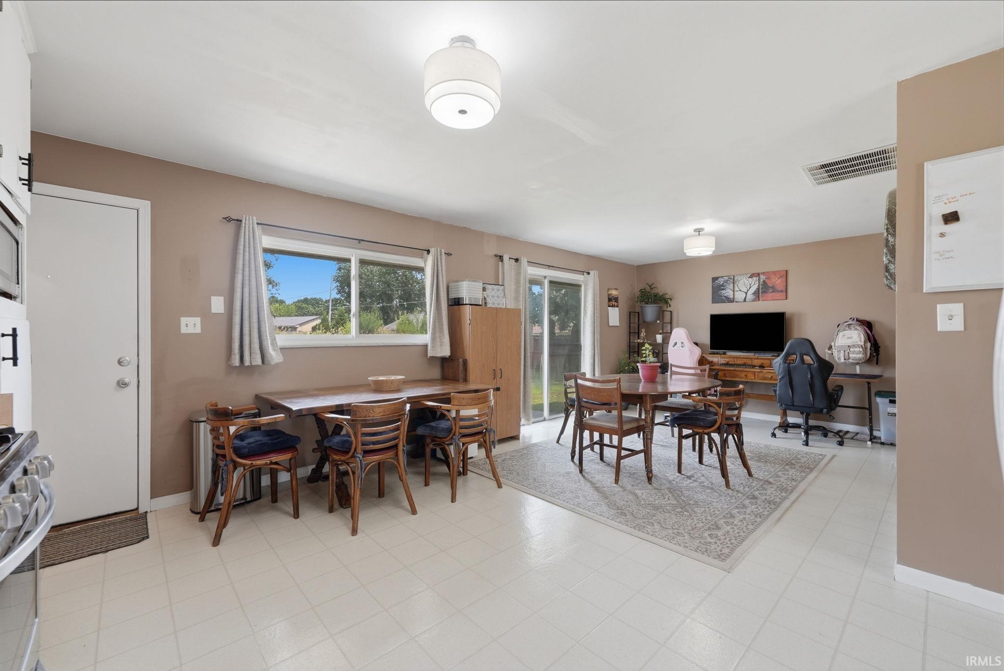 Bright, open-concept living area featuring light-toned flooring, a sliding glass door for outdoor access, and multiple windows providing natural light