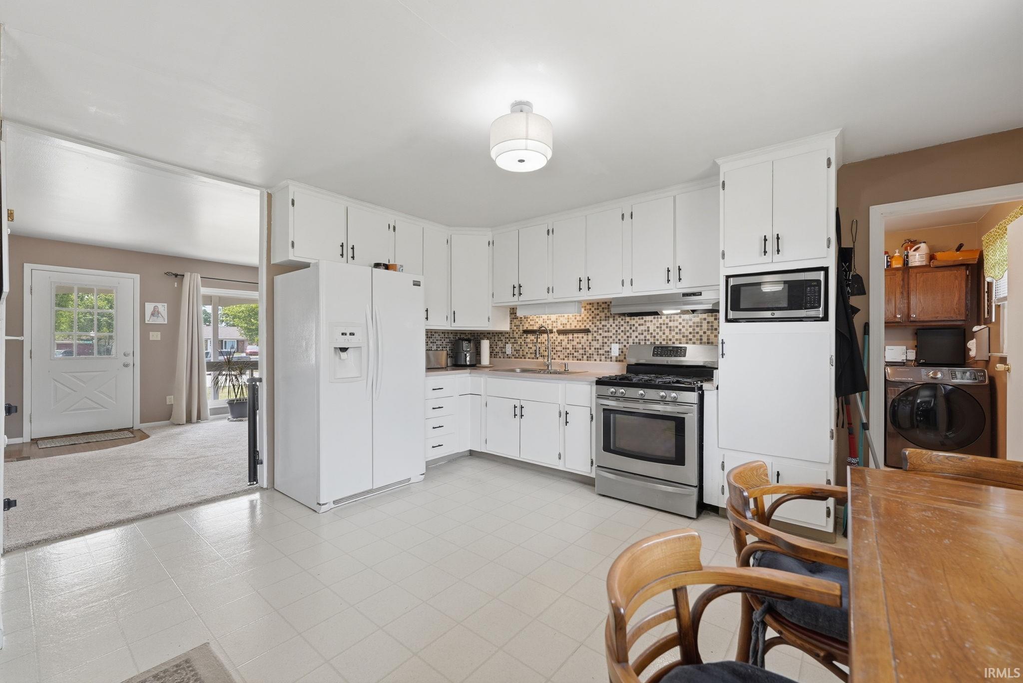 Kitchen featuring white cabinetry, a mosaic tile backsplash, and stainless steel appliances