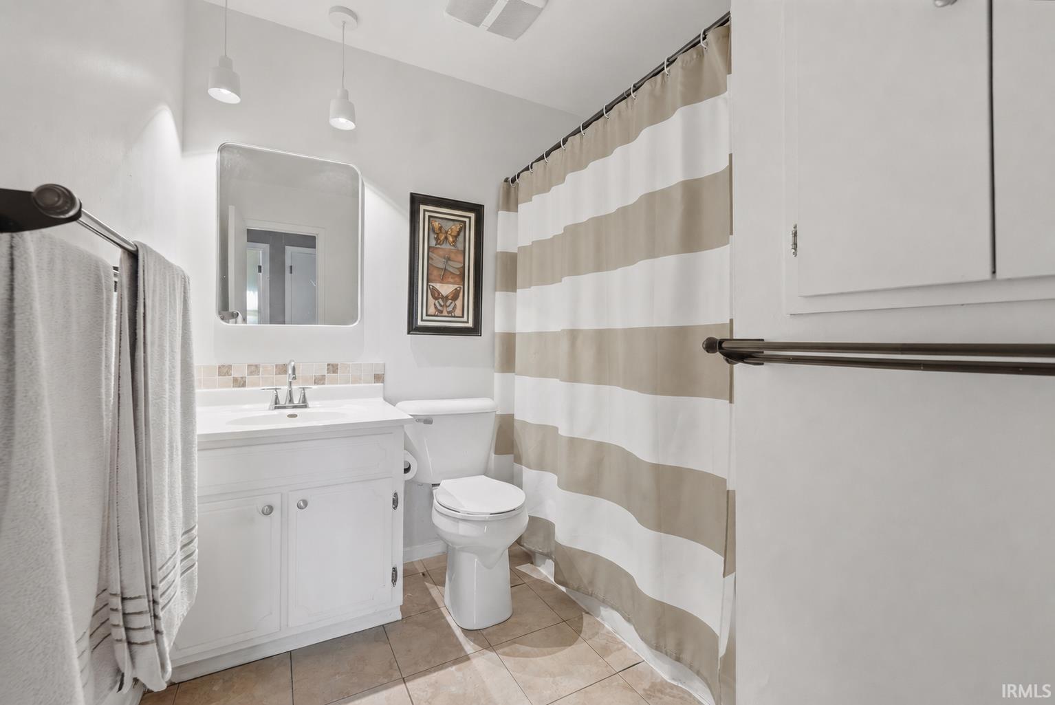 Bathroom featuring a white vanity with integrated sink, rectangular mirror, and tiled backsplash