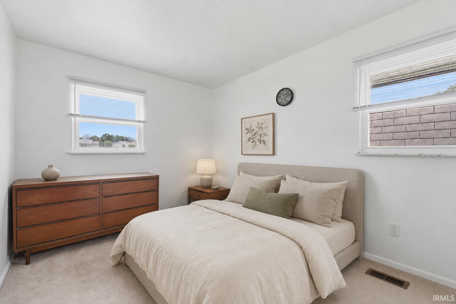 Carpeted room with white walls and two windows providing natural light