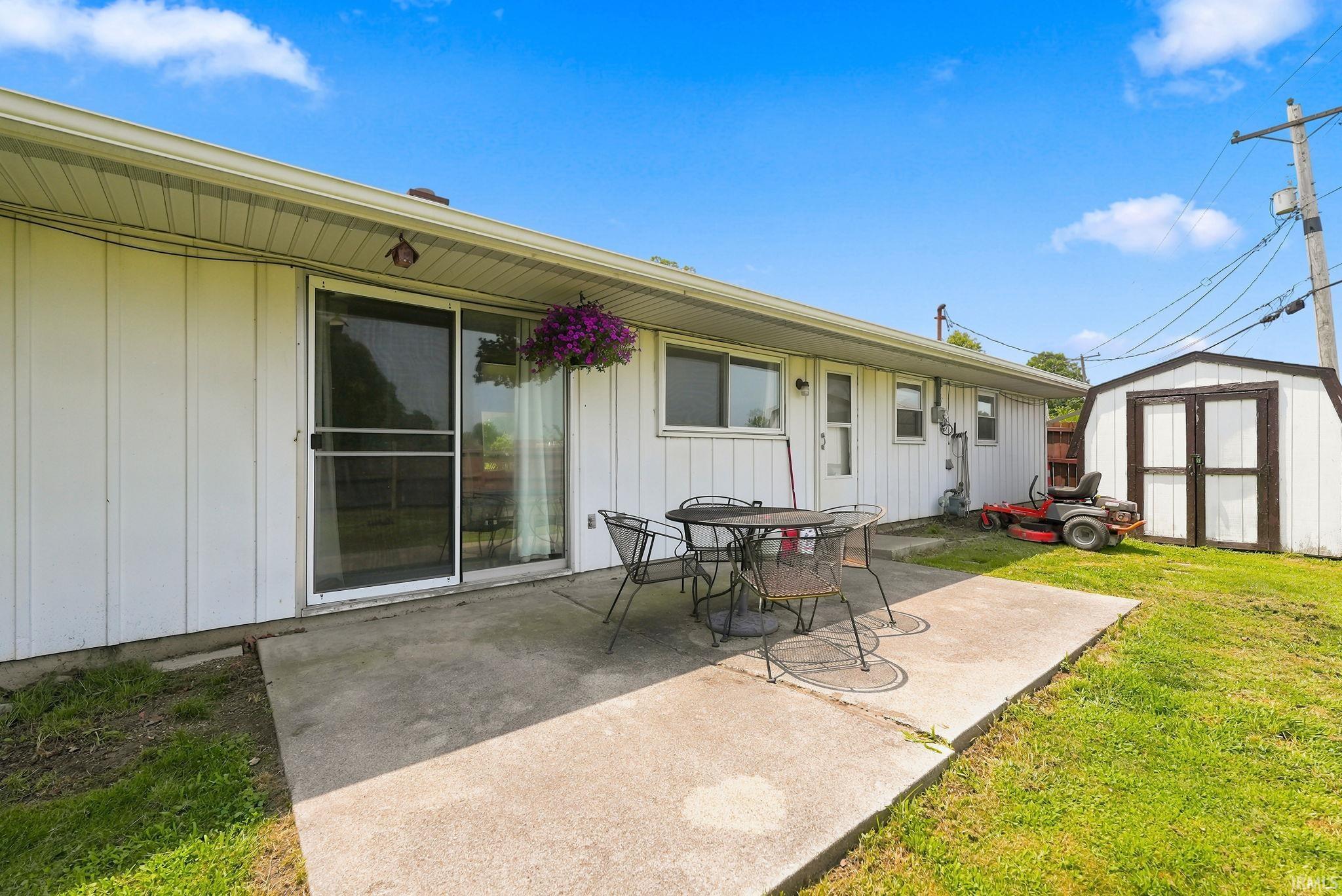 Rear exterior featuring white vertical siding and an expansive concrete patio