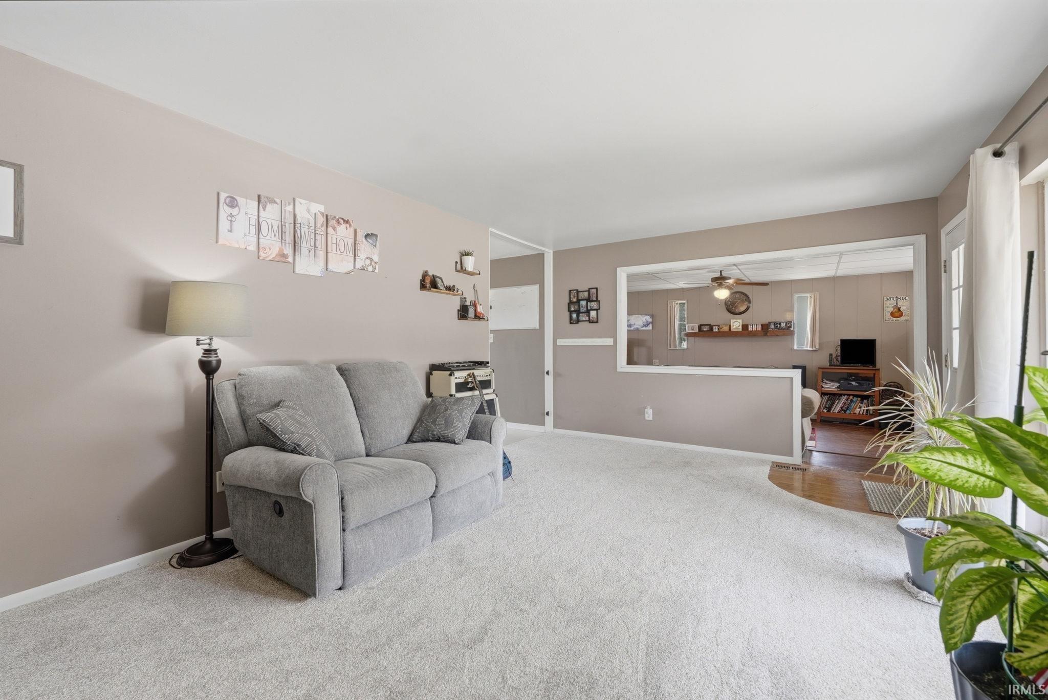 Spacious living area featuring light-toned carpeting and neutral wall tones