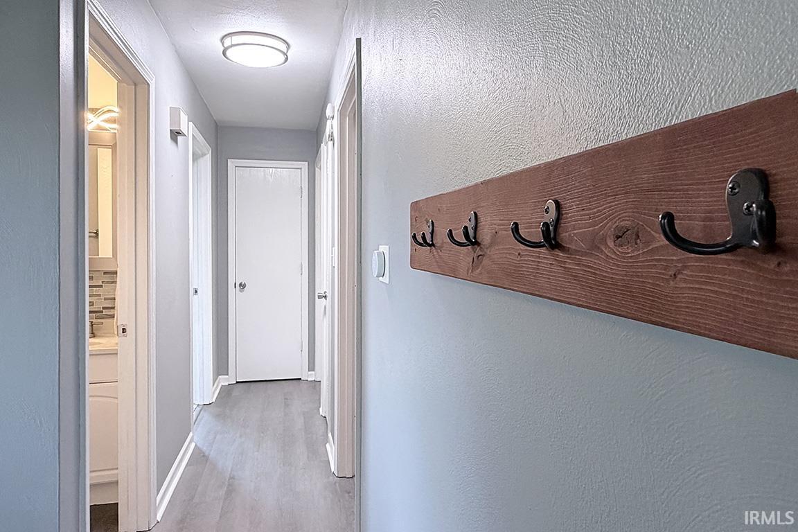 Hallway featuring wood-finish flooring, light gray walls, and white trim