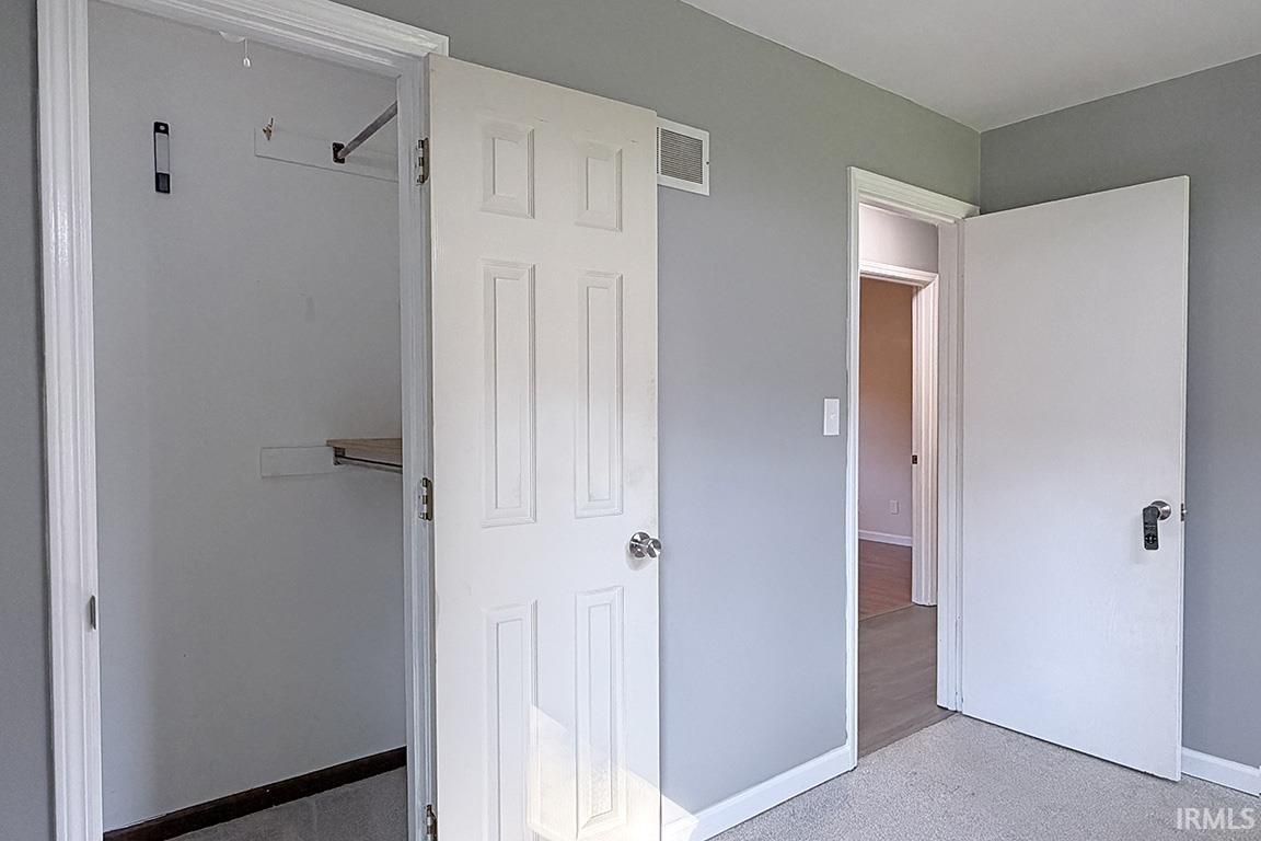 Spacious bedroom featuring soft sage-green walls, neutral carpeting, and abundant natural light