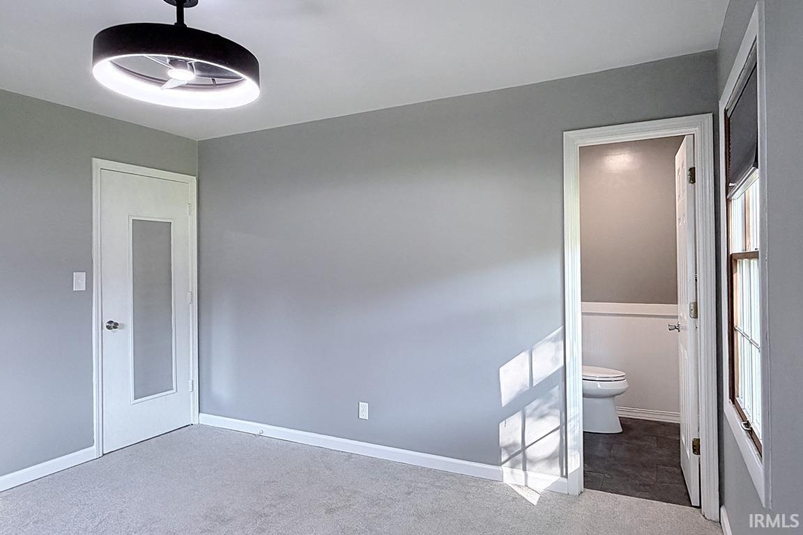 Spacious bedroom featuring neutral gray walls, soft-finish carpet flooring, and abundant natural light from multiple windows