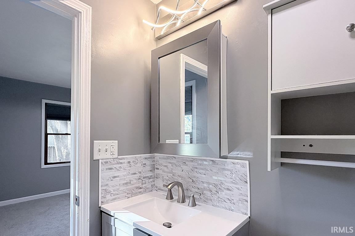 Bathroom vanity with a rectangular undermount sink, brushed nickel faucet, and a mosaic tile backsplash