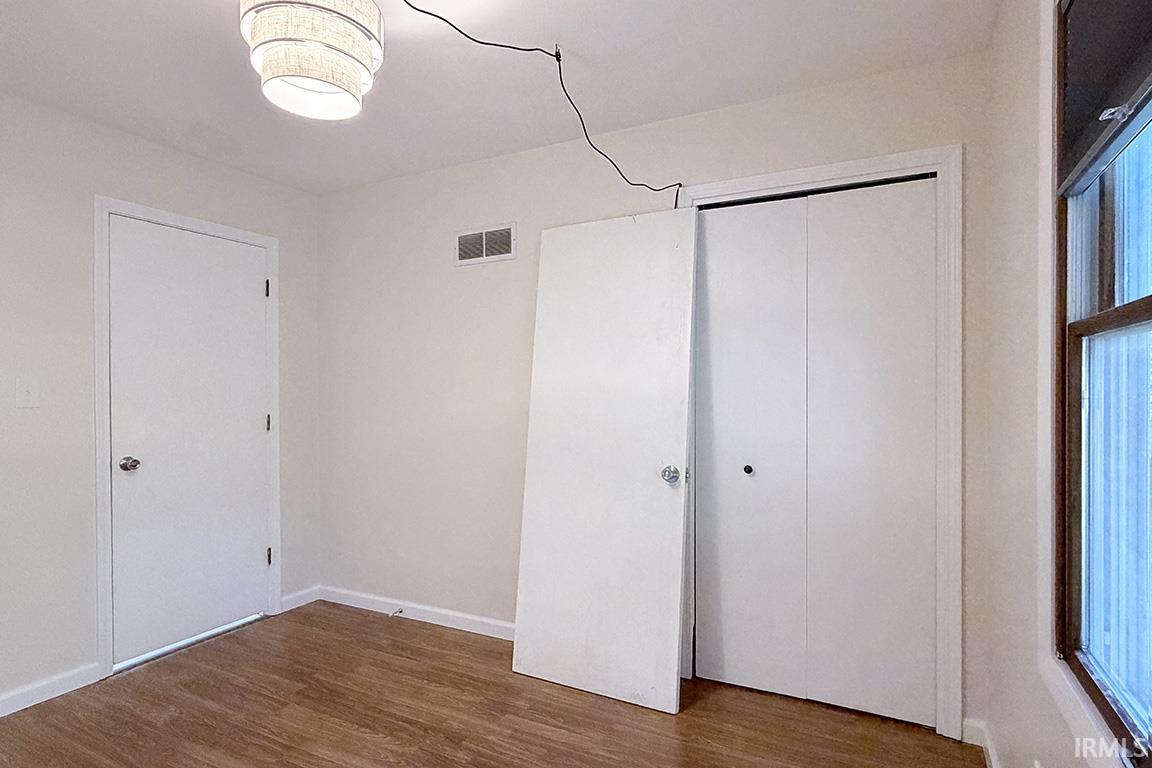 Bright, versatile interior space featuring hardwood flooring, multiple closet storage options with white panel doors, recessed ceiling lighting, and clean white walls with excellent natural light from large windows