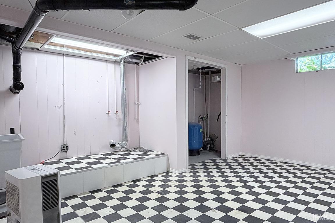 Finished basement space featuring classic black-and-white checkered flooring, recessed ceiling lighting, and separate storage areas