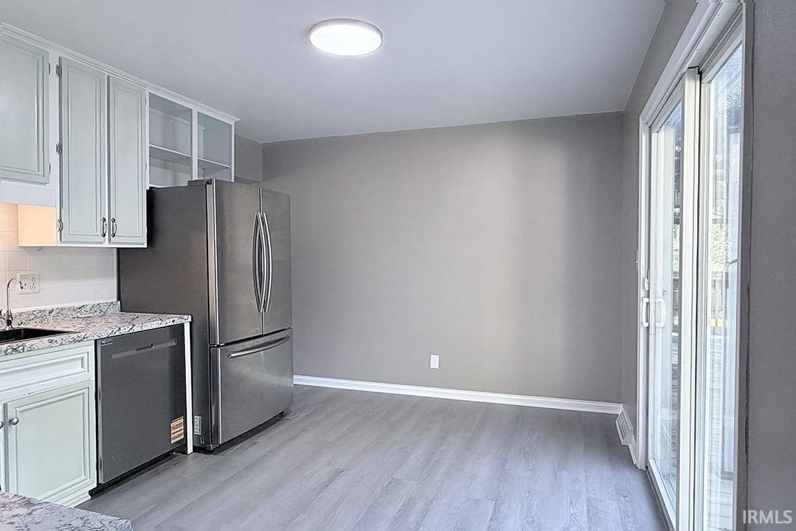 Well-appointed kitchen and dining area featuring light-toned cabinetry, stainless steel appliances, granite-style countertops, and light wood-finish flooring