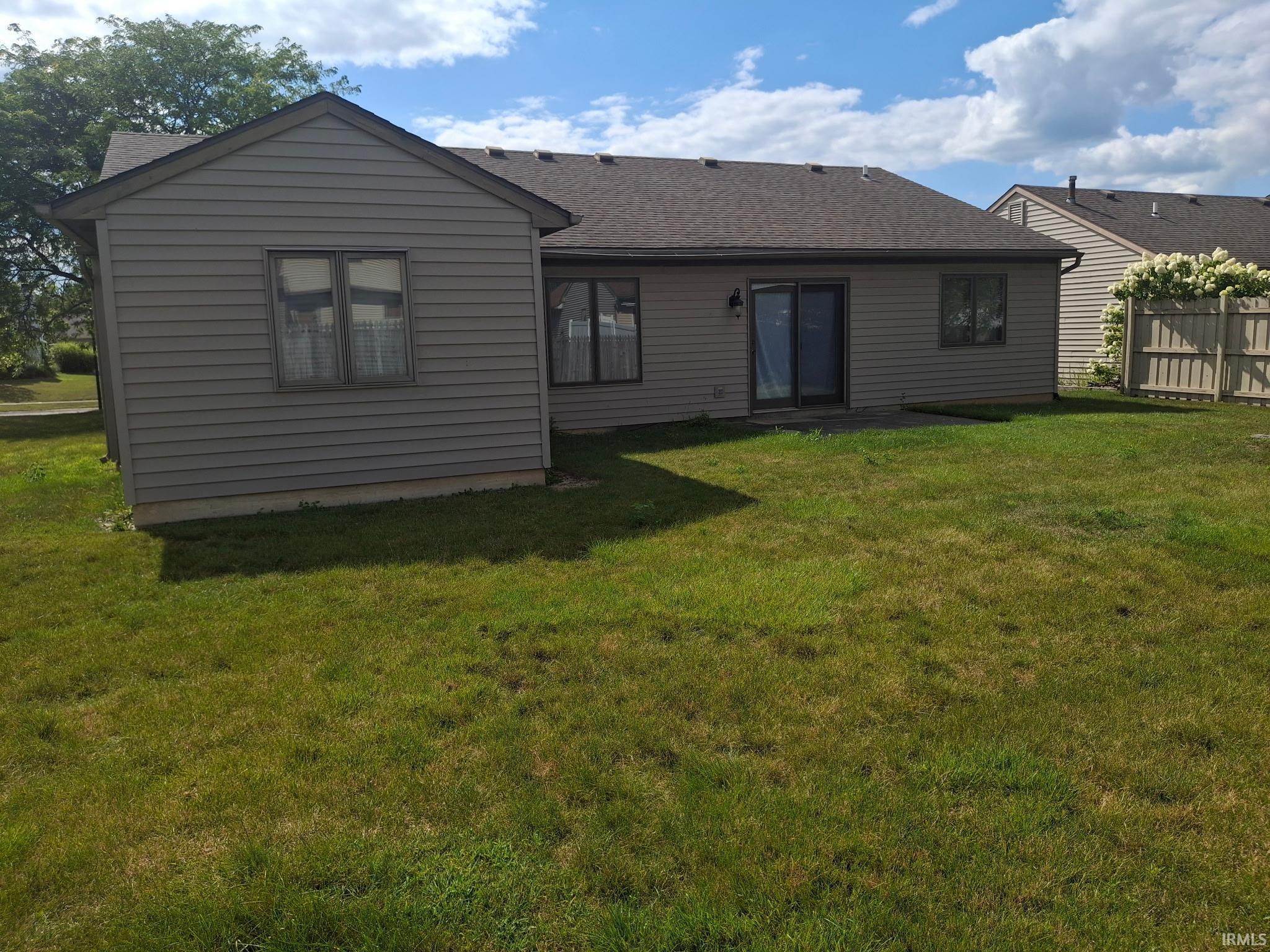Expansive rear yard featuring a paved patio, sliding glass door access, and perimeter fencing