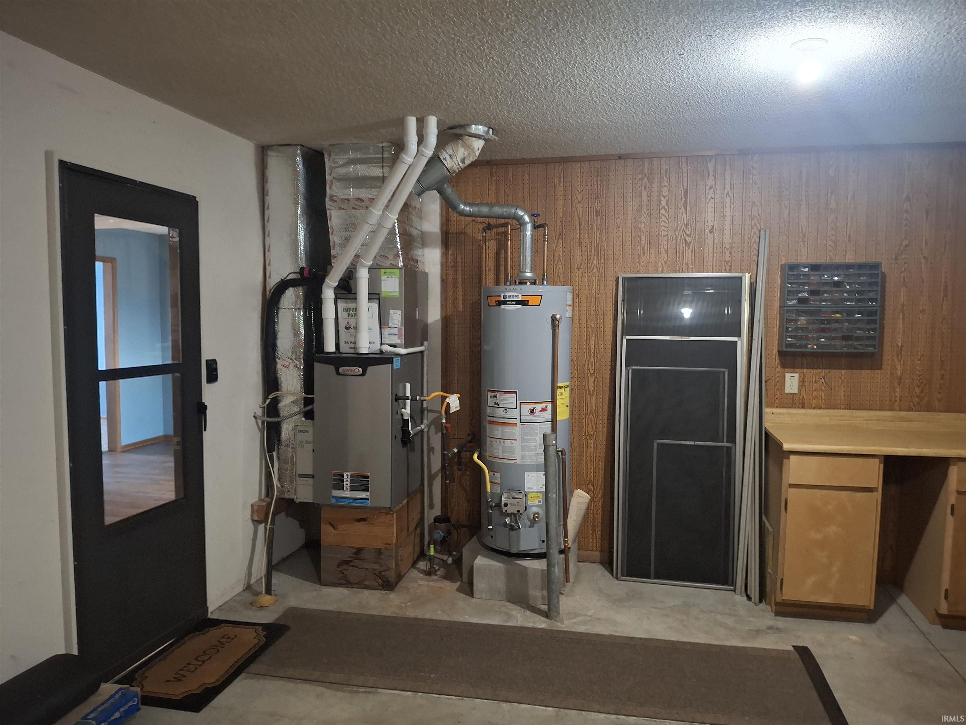 Dedicated utility area featuring a water heater, furnace, and a built-in wood-finish countertop with cabinetry
